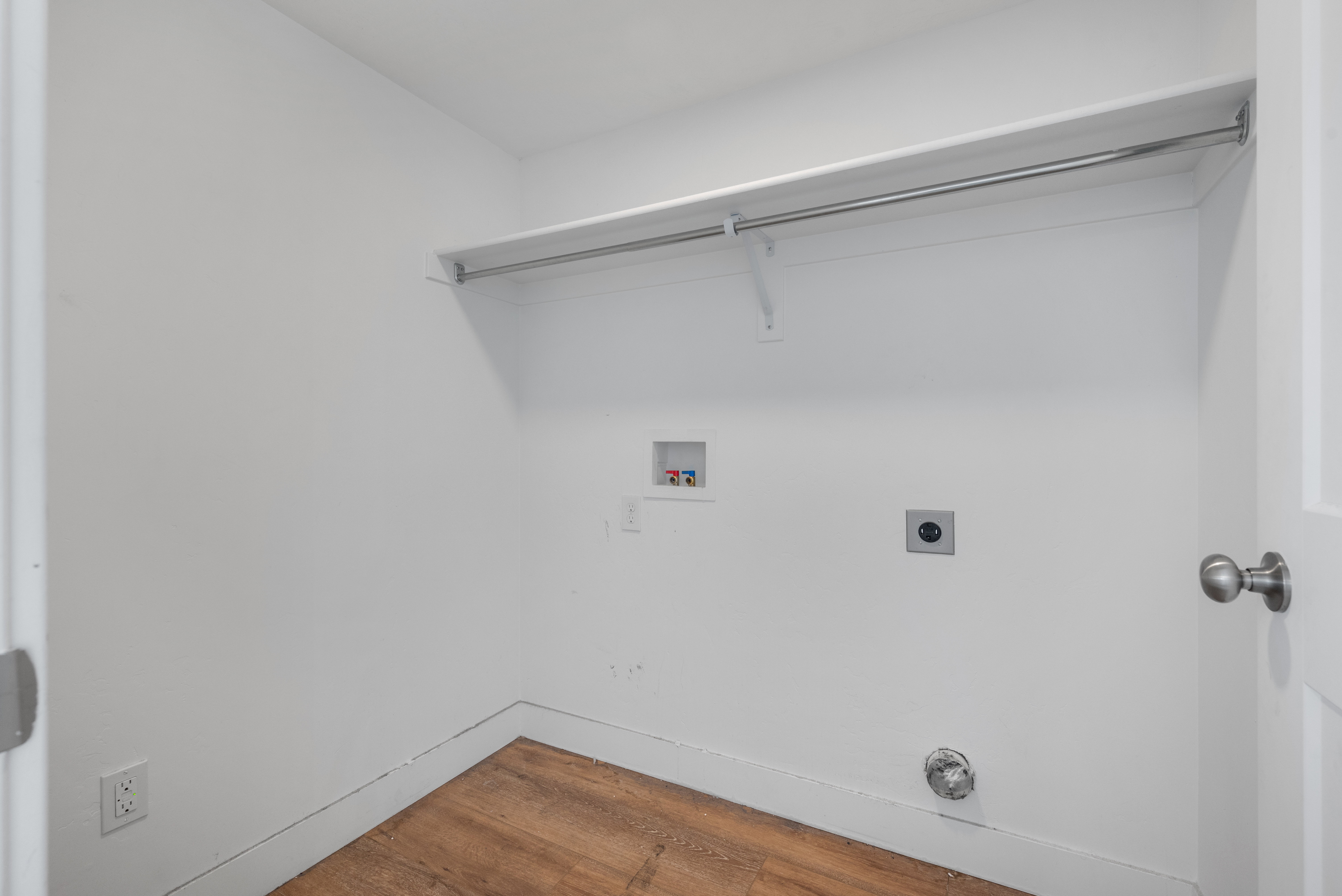 Dedicated laundry space featuring wood-finish flooring and white walls