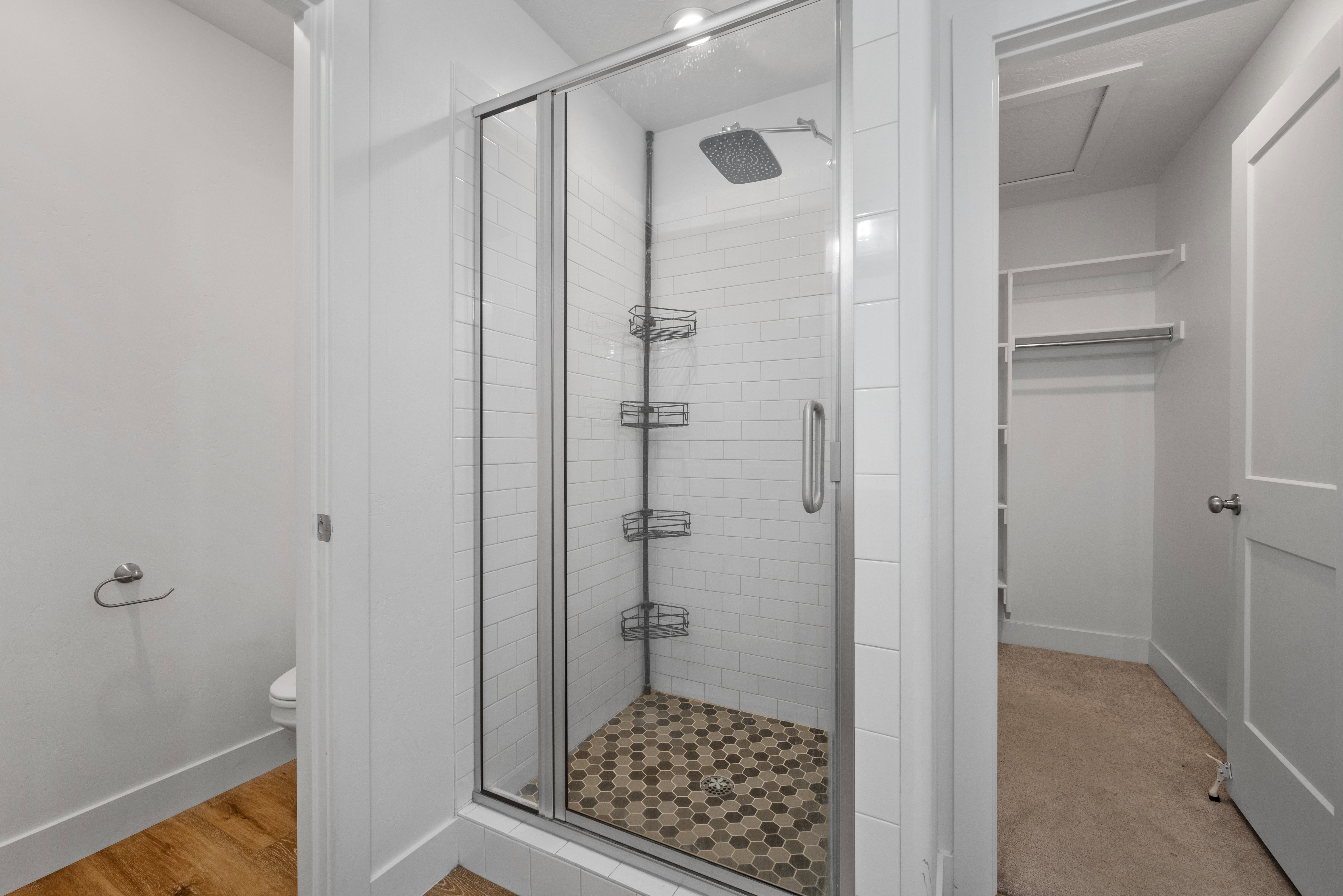 Glass-enclosed shower featuring subway tile surround, hexagonal tile flooring, and a rainfall showerhead