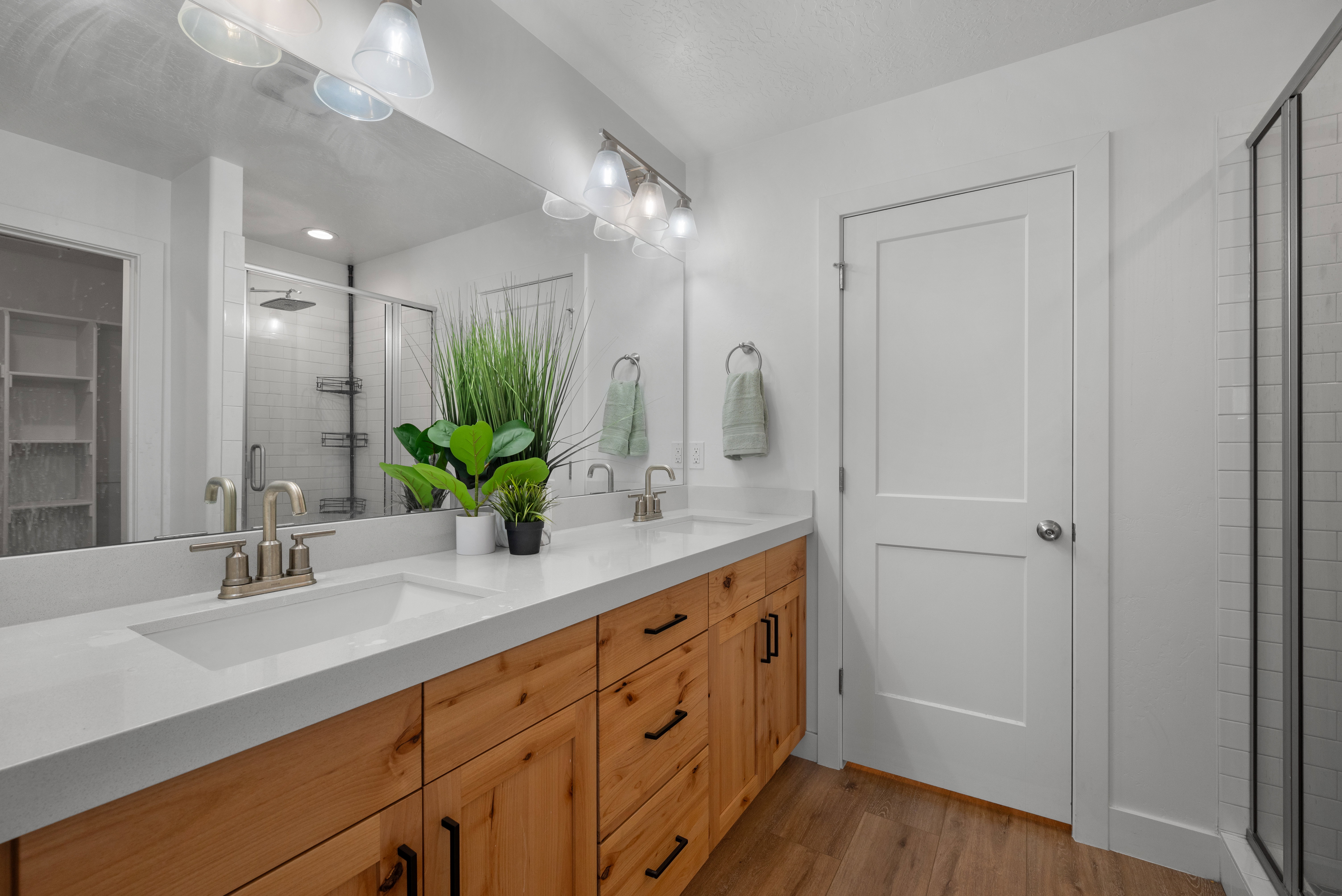 Bathroom off the primary bedroom.  Dual sink vanity featuring light wood-finish cabinetry with black hardware, white countertops, and brushed nickel fixtures