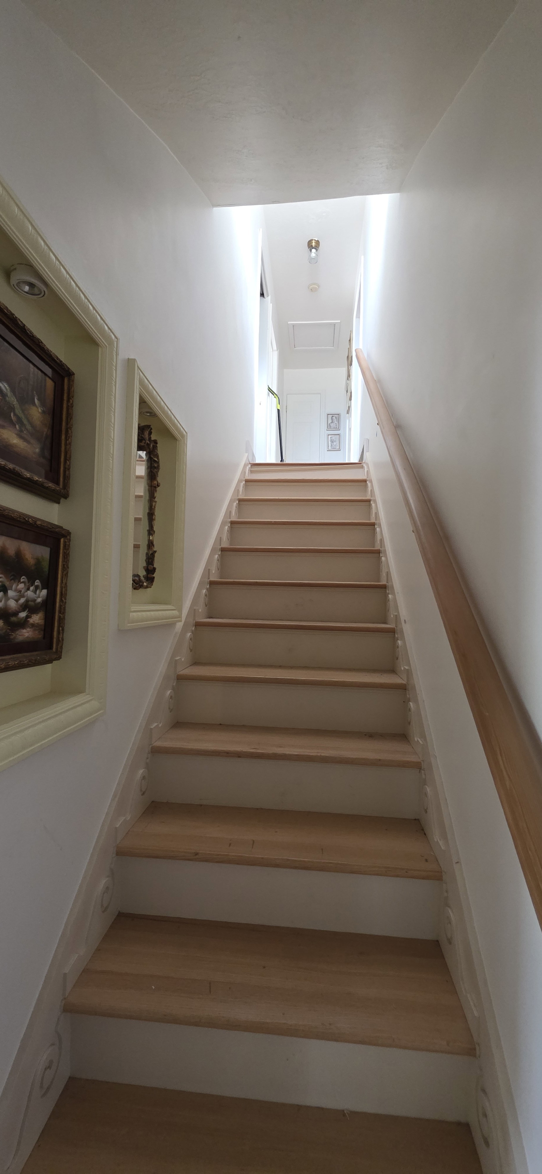 Light wood-finish staircase with white risers and a natural wood handrail