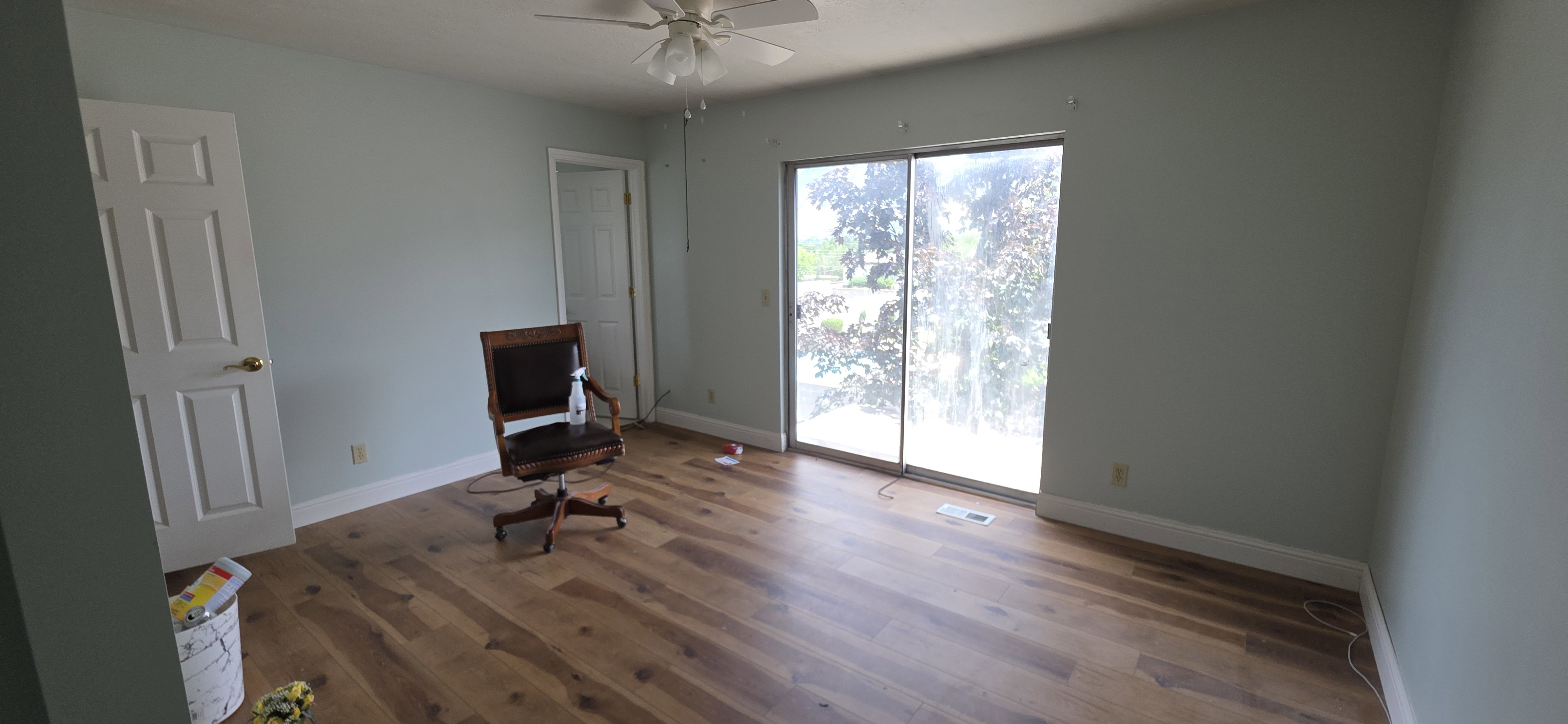 Room featuring wood-finish flooring, light blue wall finishes, white trim, and a ceiling fan