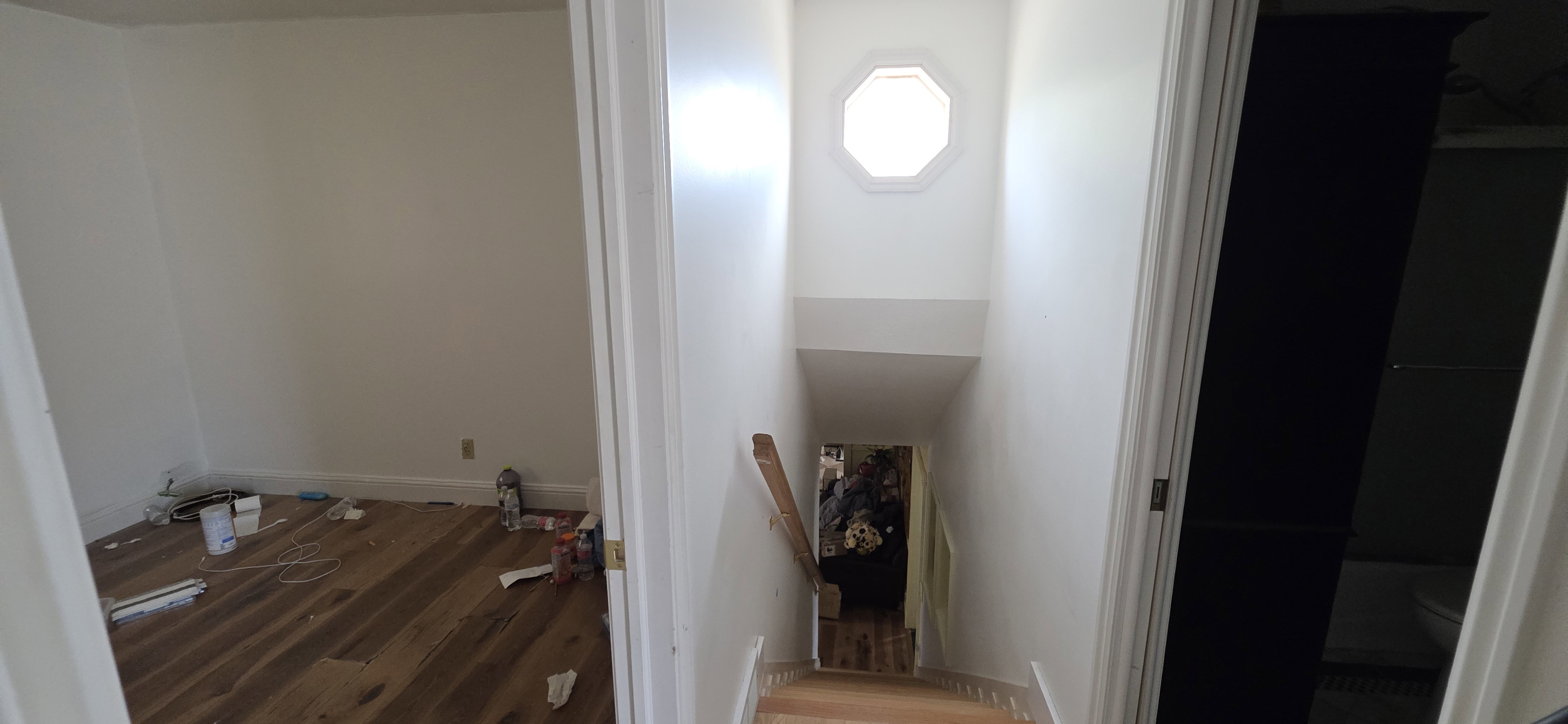 Stairwell featuring an octagonal window, natural wood handrail, and wood-finish stair treads