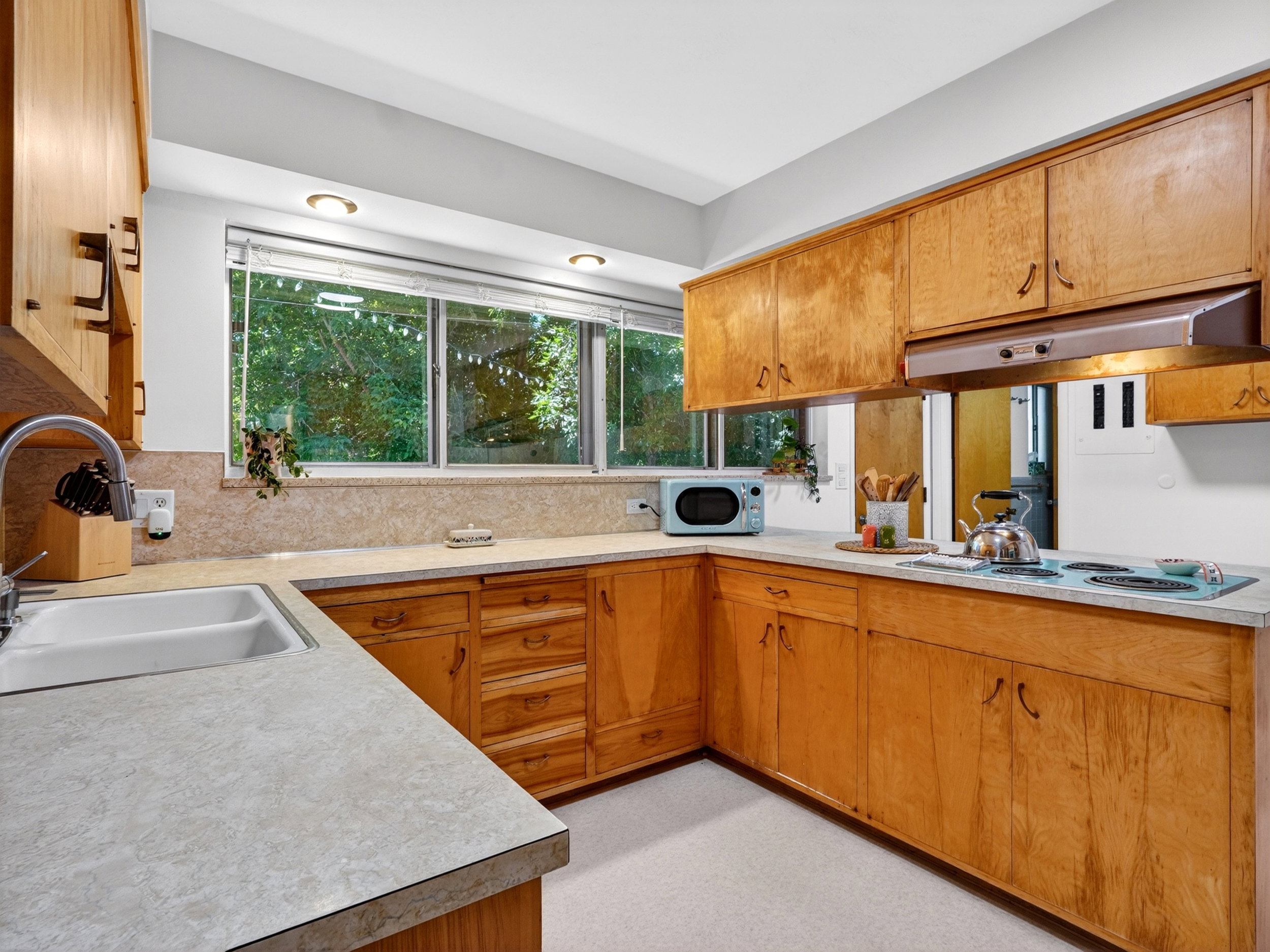 Open kitchen with range hood and robin's egg blue retro cooktop and matching microwave.
