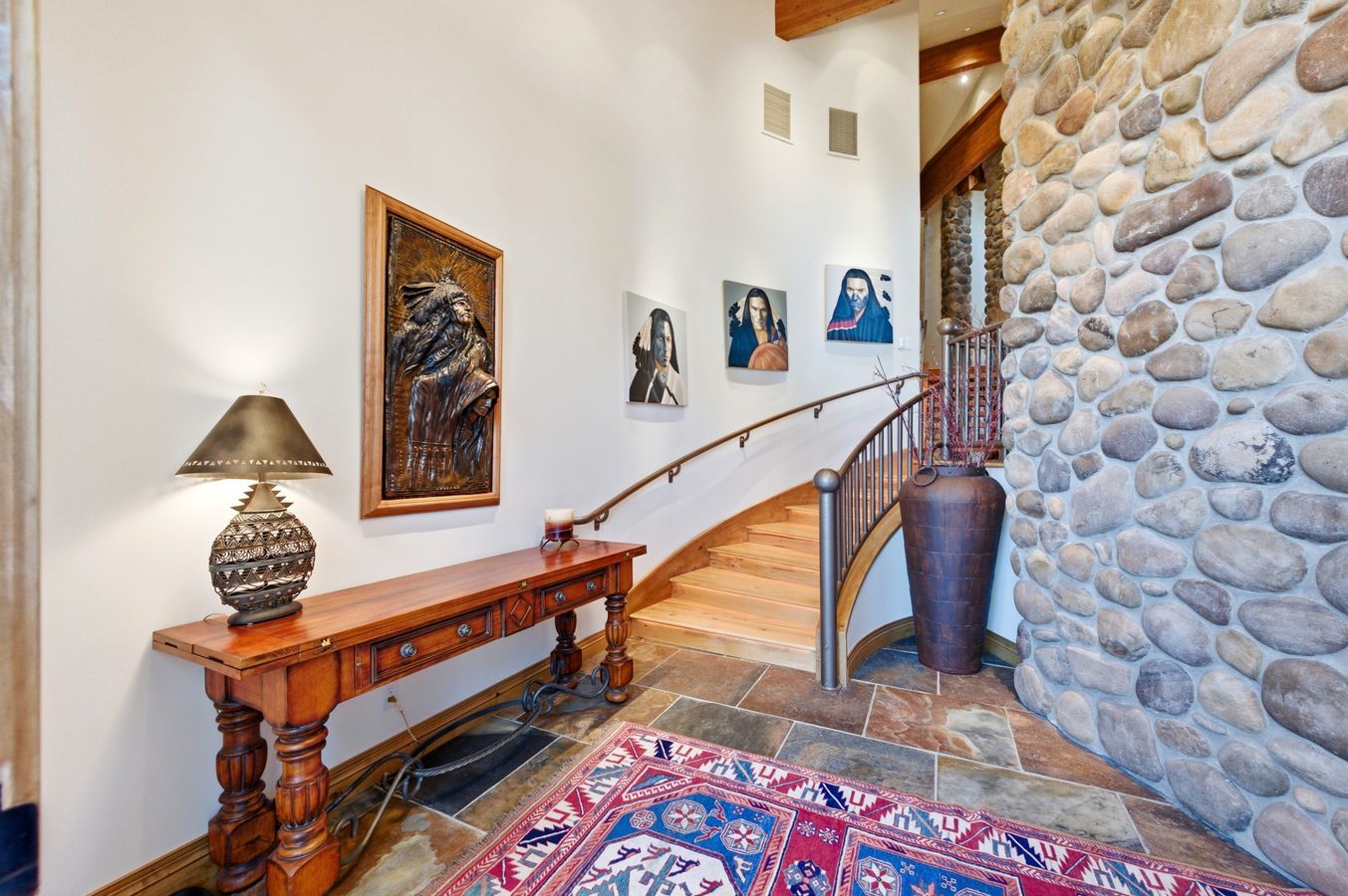Entryway featuring a stone accent wall, natural wood staircase with a metal railing, and slate tile flooring