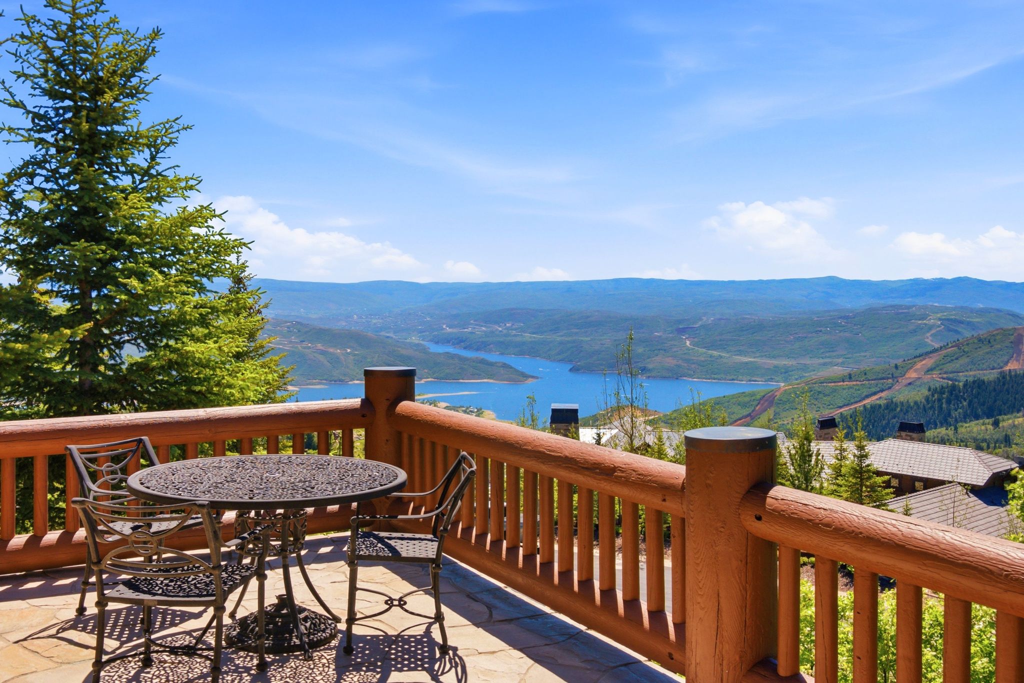 Stone patio with a log railing overlooking a large lake and distant mountains