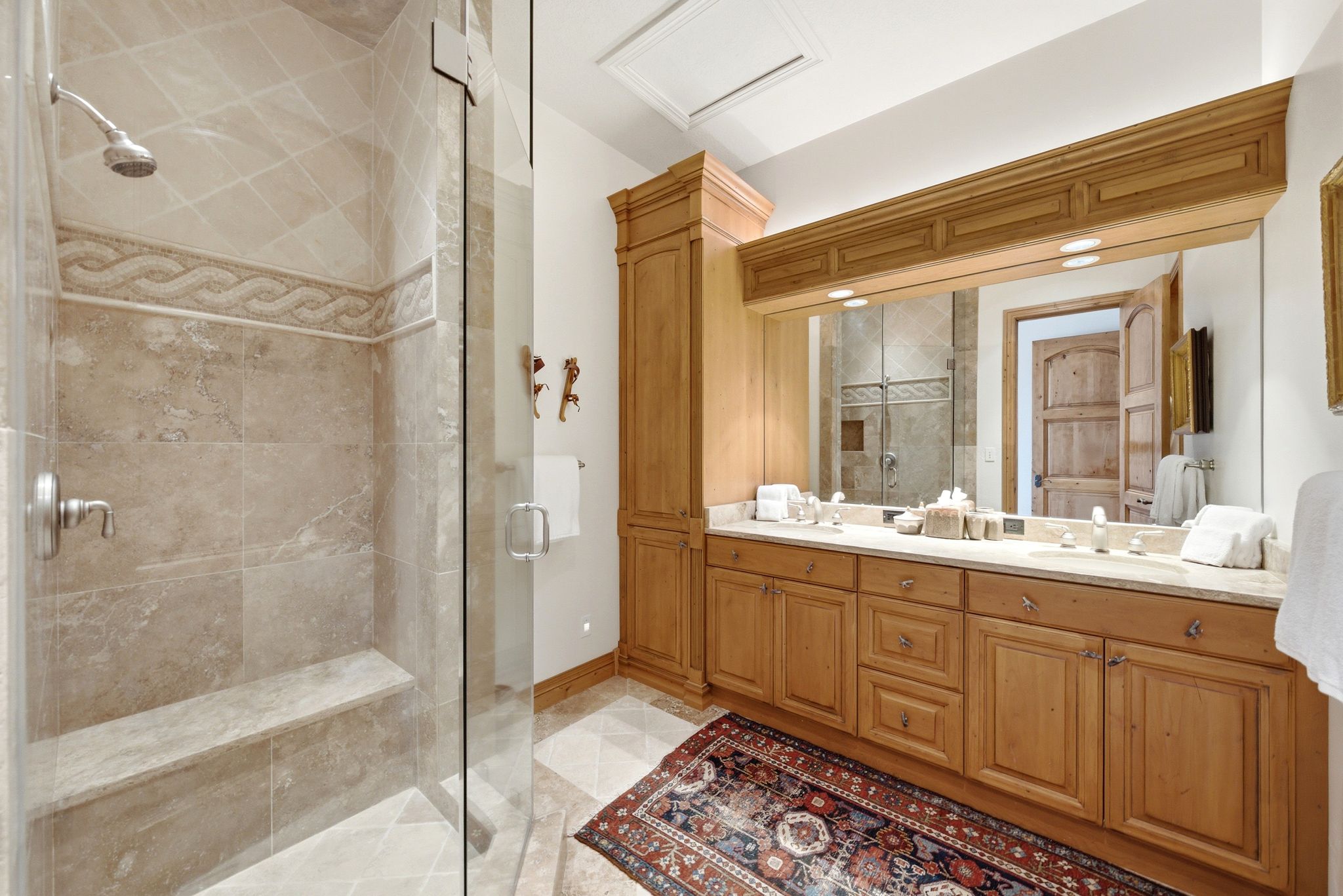 Glass-enclosed shower with a built-in bench and decorative tile inlay
