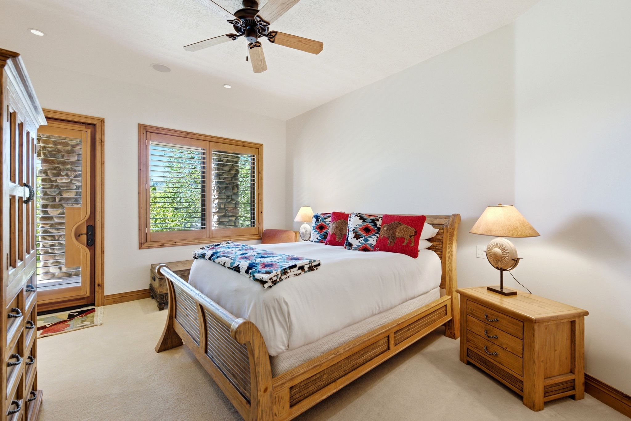 Carpeted room featuring a ceiling fan, recessed lighting, wood-framed window with louvered shutters, and a wood-framed door with a glass panel