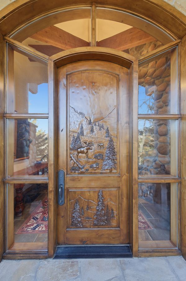 Custom carved wooden entry door featuring unique wildlife and landscape detailing