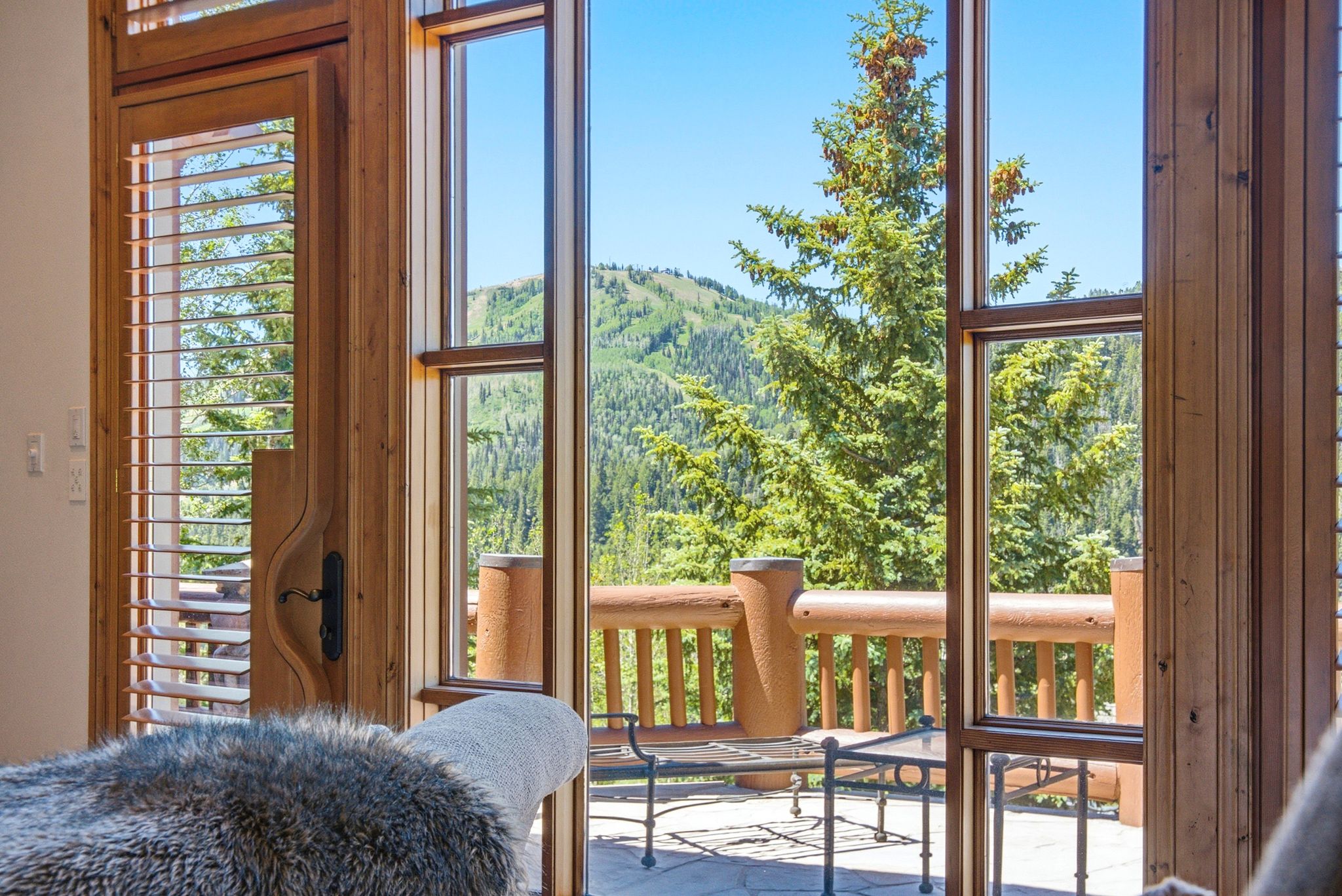 Expansive floor-to-ceiling windows with natural wood framing overlooking a mountain and tree landscape