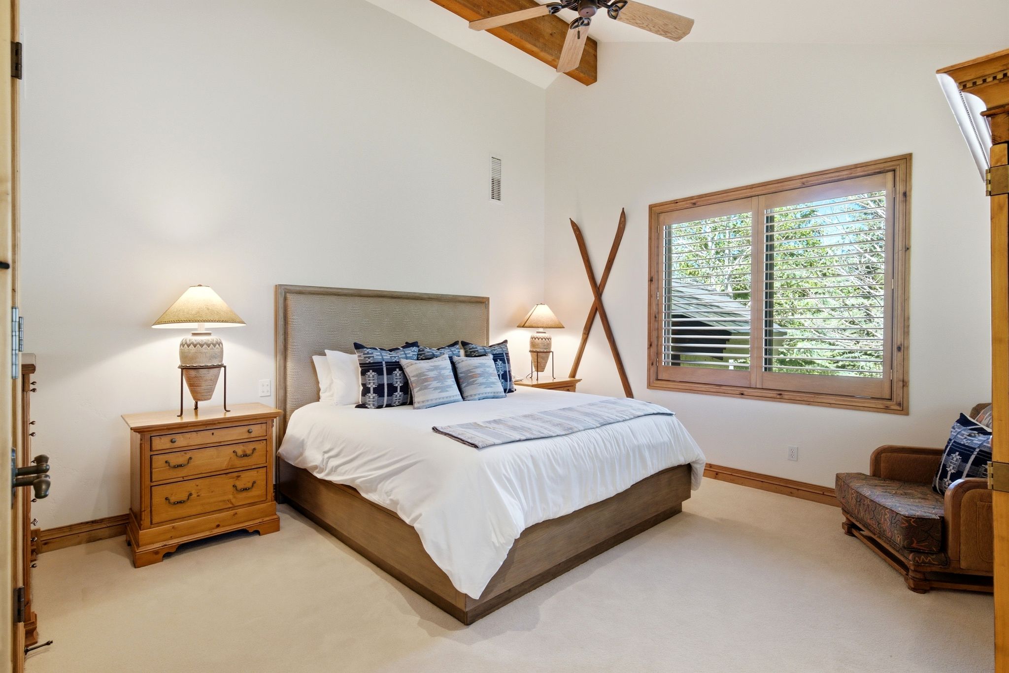 Bedroom featuring vaulted ceilings with exposed wood beams, a ceiling fan, and light-toned carpeting