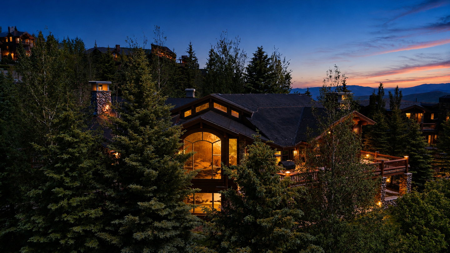 Multi-level property featuring a prominent arched picture window, stone chimney, and a spacious wooden deck