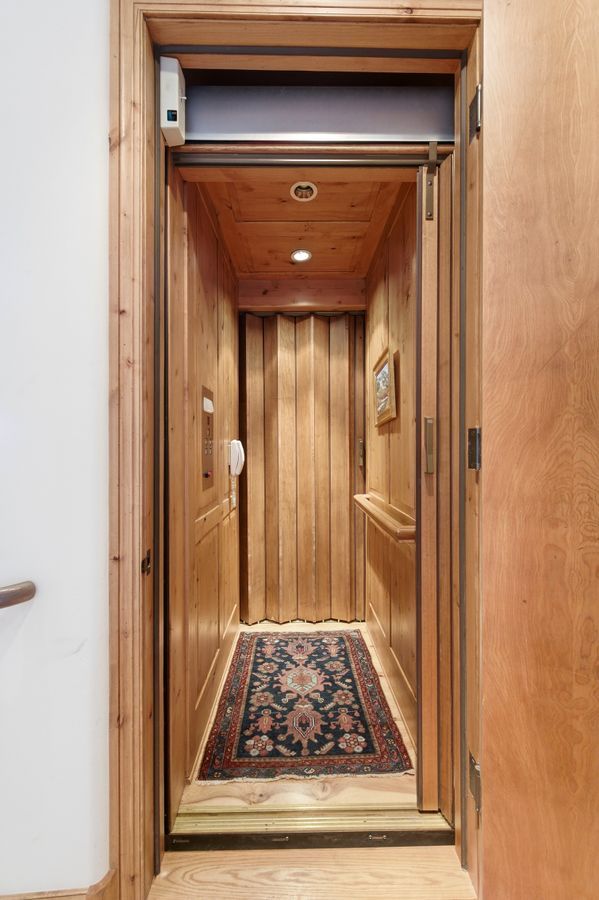 Private in-home elevator featuring wood paneling, recessed lighting, accordion-style door, and a decorative floor runner