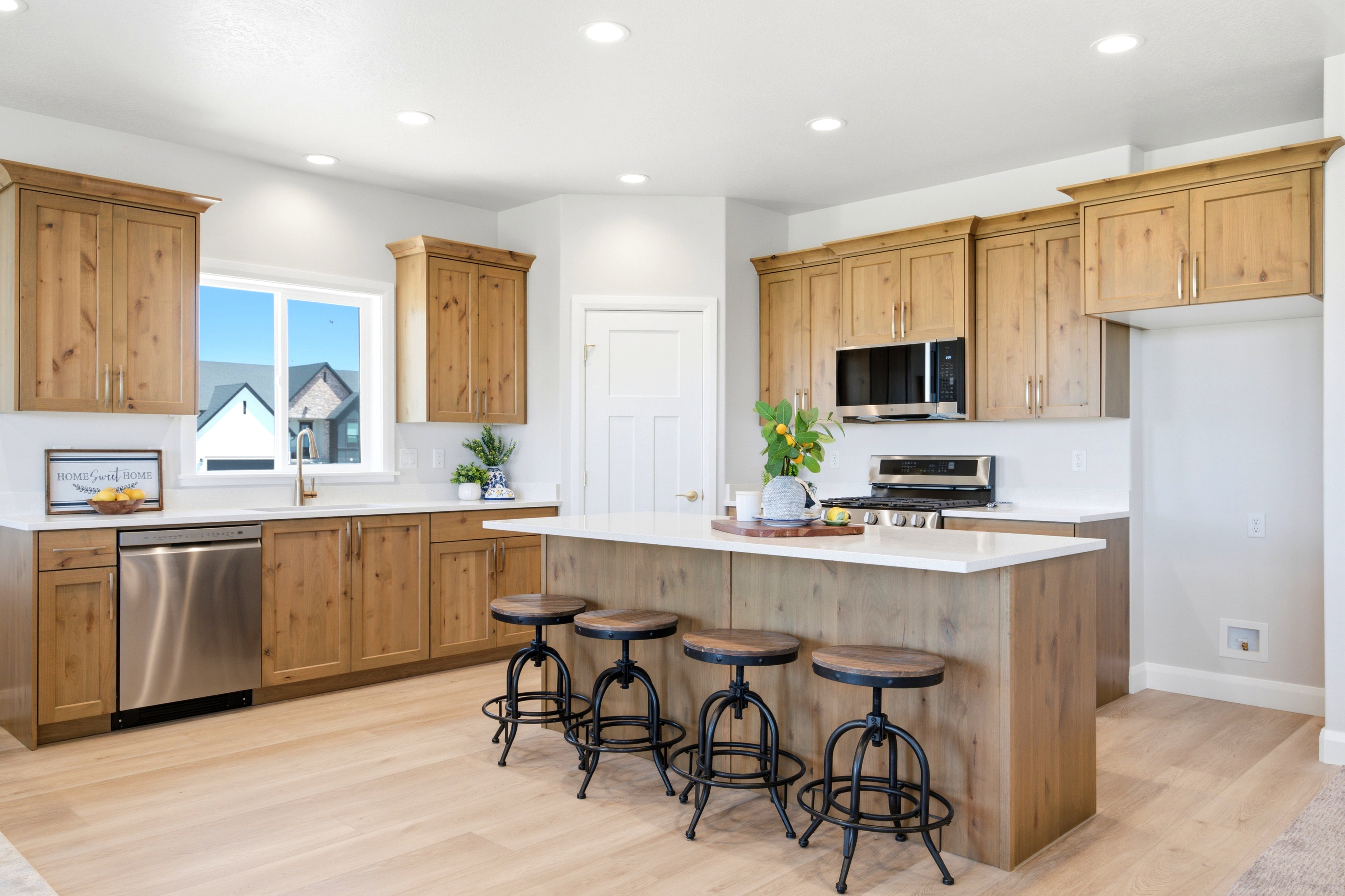 Kitchen featuring an expansive island with seating, natural wood-finish cabinetry, light-toned countertops, and recessed lighting