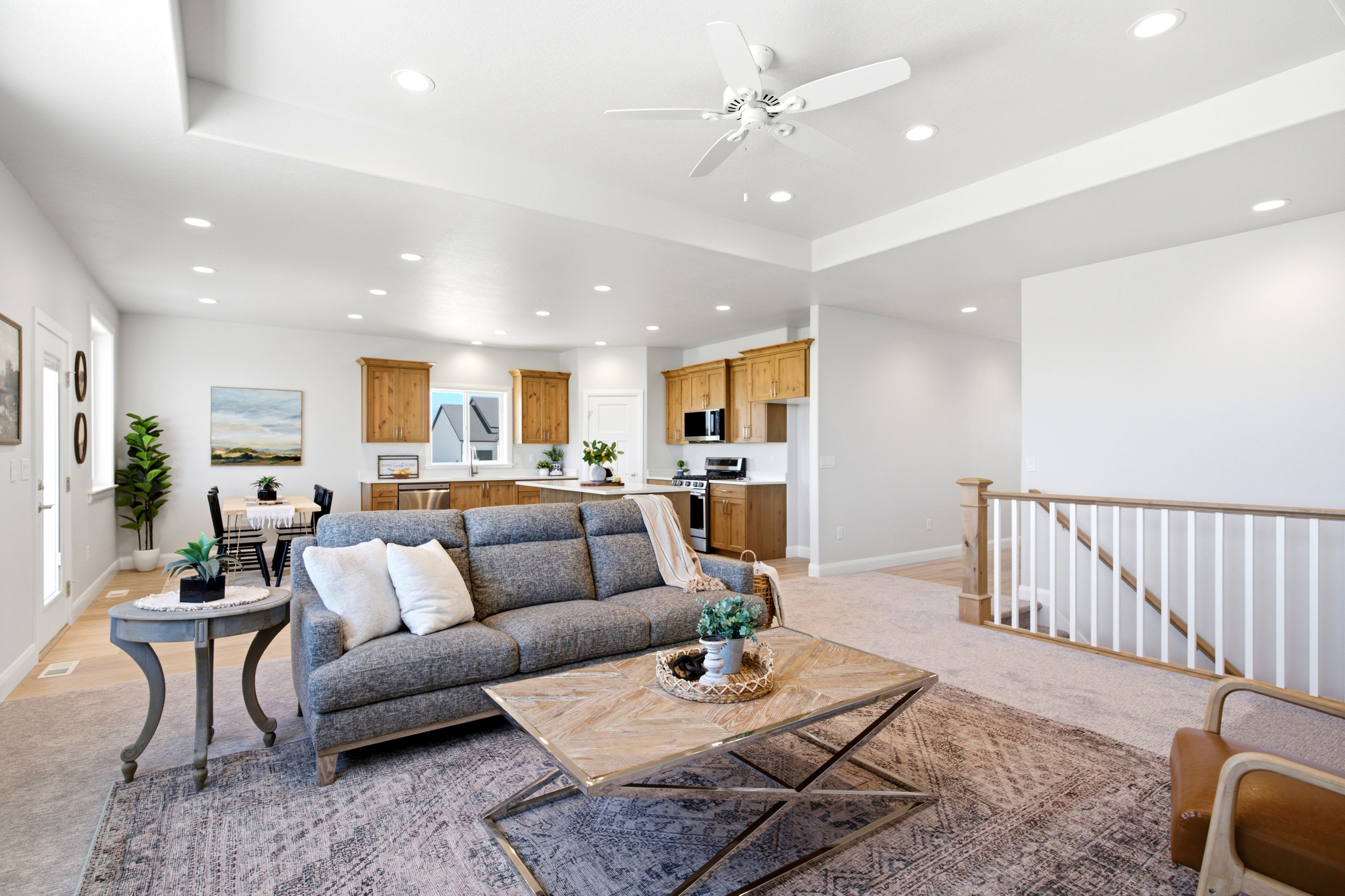 Bright open-concept living area featuring a tray ceiling, recessed lighting, and a ceiling fan