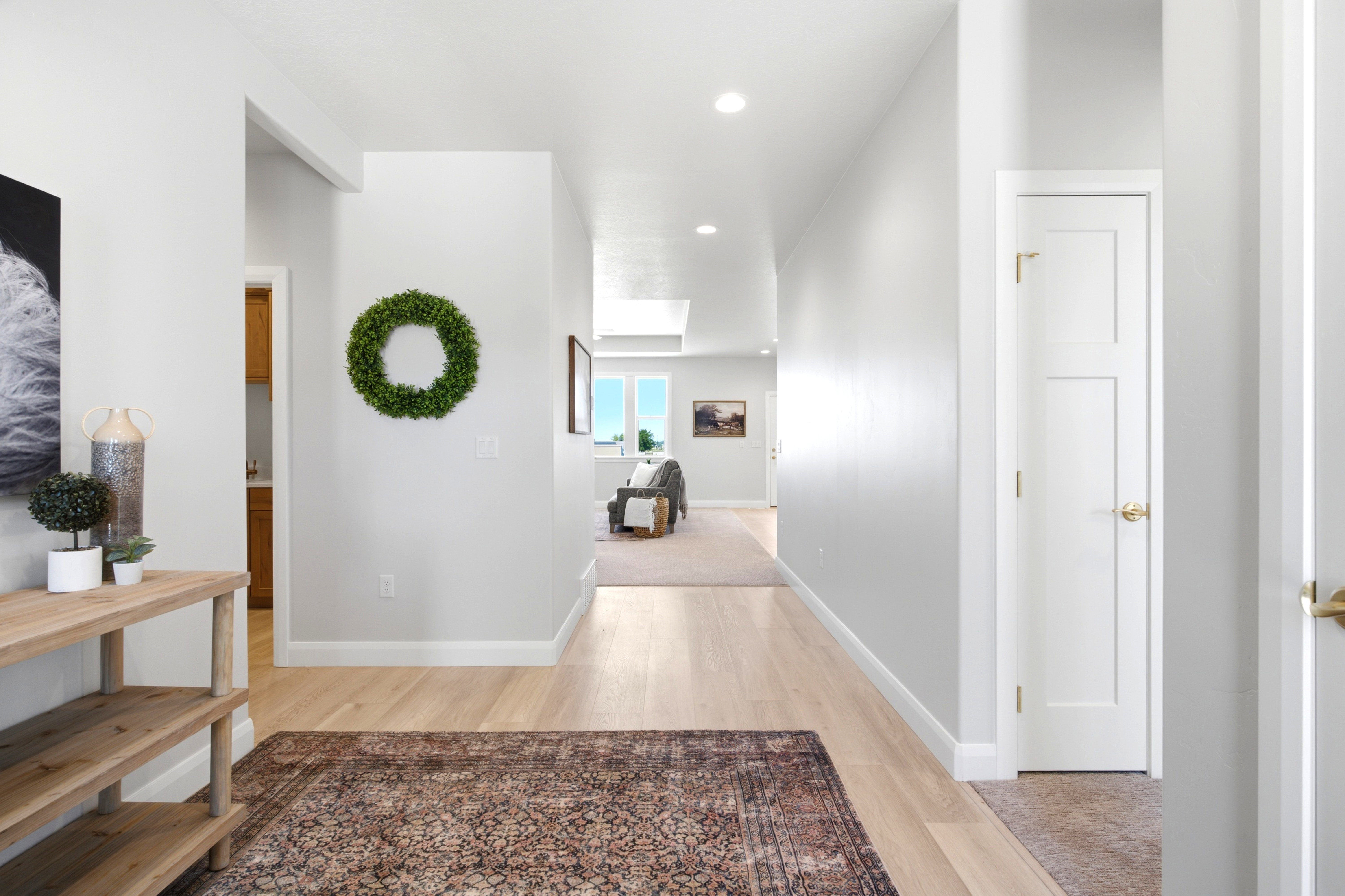 Wide hallway featuring light wood-finish flooring, recessed lighting, and bright white walls