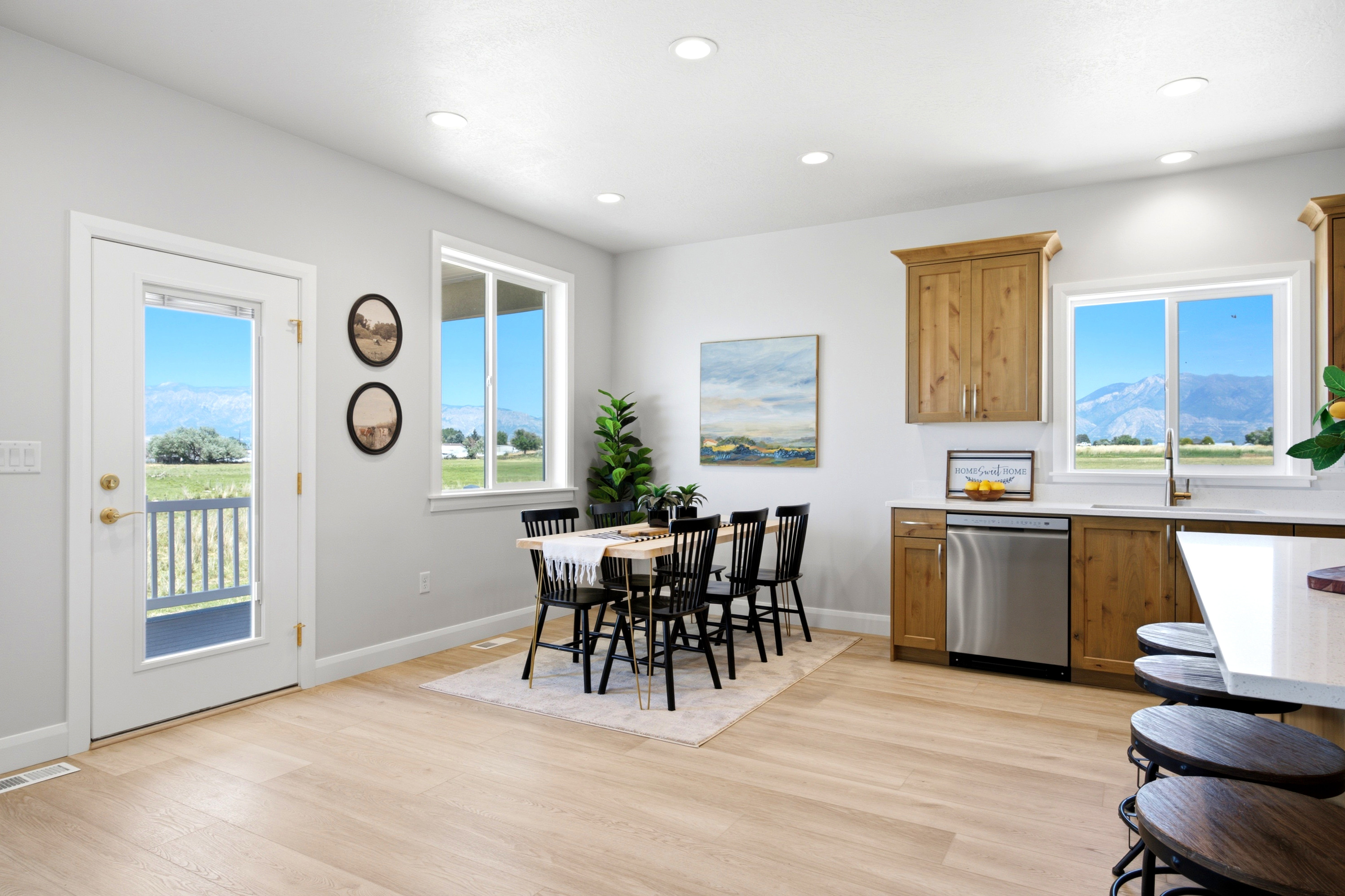 Bright kitchen and dining area with wood-finish flooring, recessed lighting, and white walls