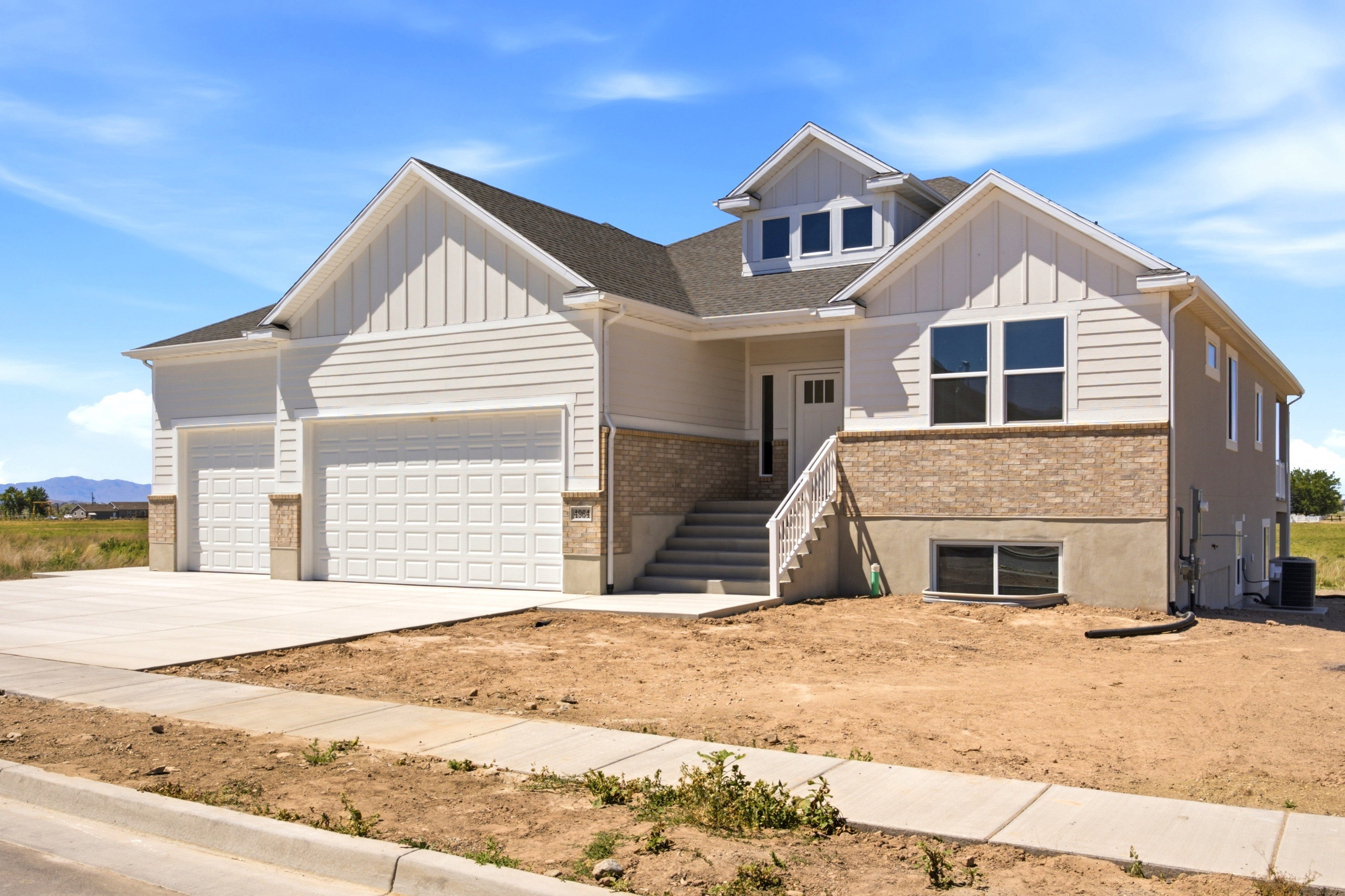 Contemporary exterior with a prominent two-car garage, brick veneer accents, and horizontal siding