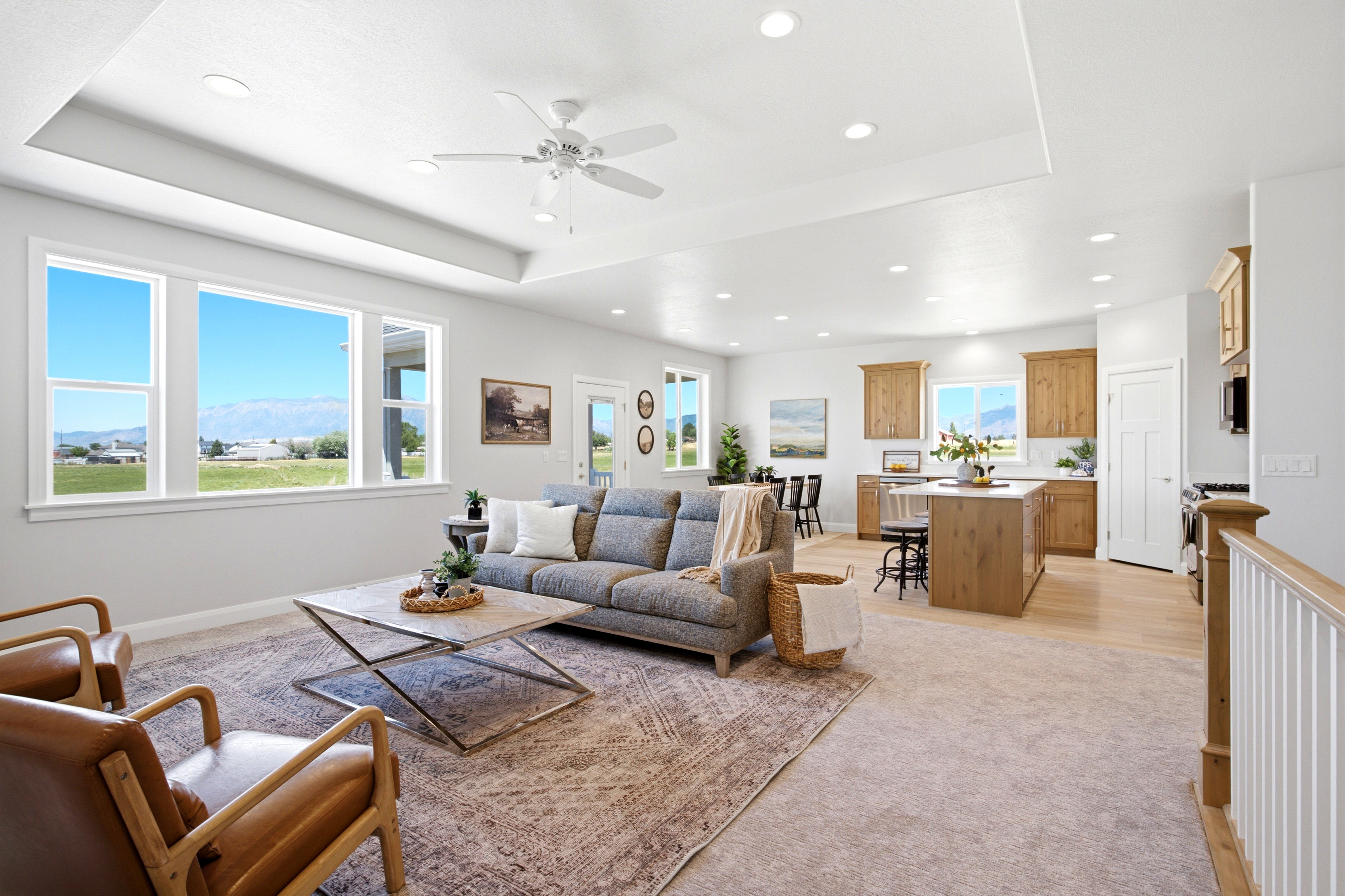 Open-concept living space featuring a tray ceiling with recessed lighting and a ceiling fan, a wall of windows, light wood-finish flooring, and natural wood cabinetry