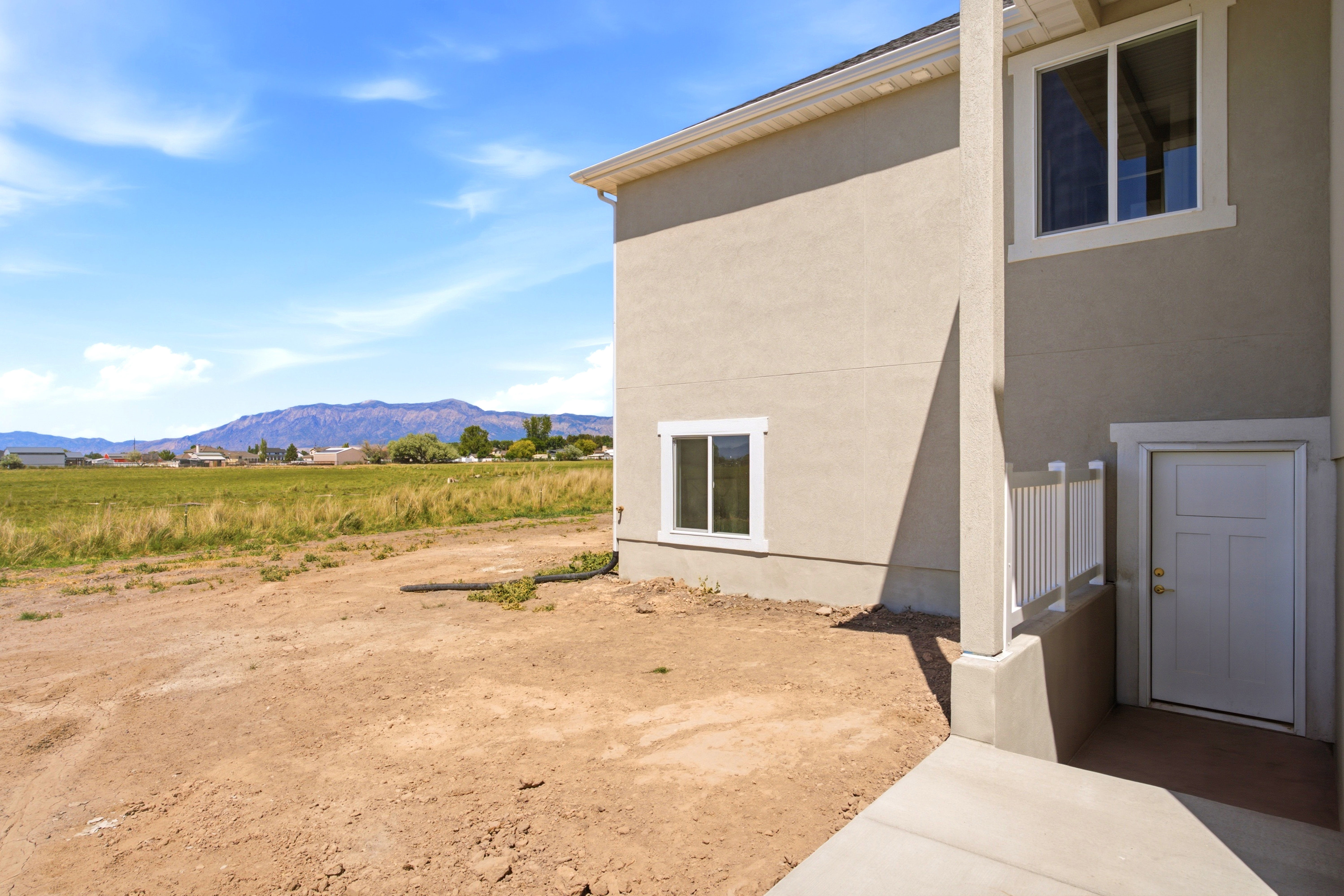 Stucco exterior with white trim details and an exterior door with white railing