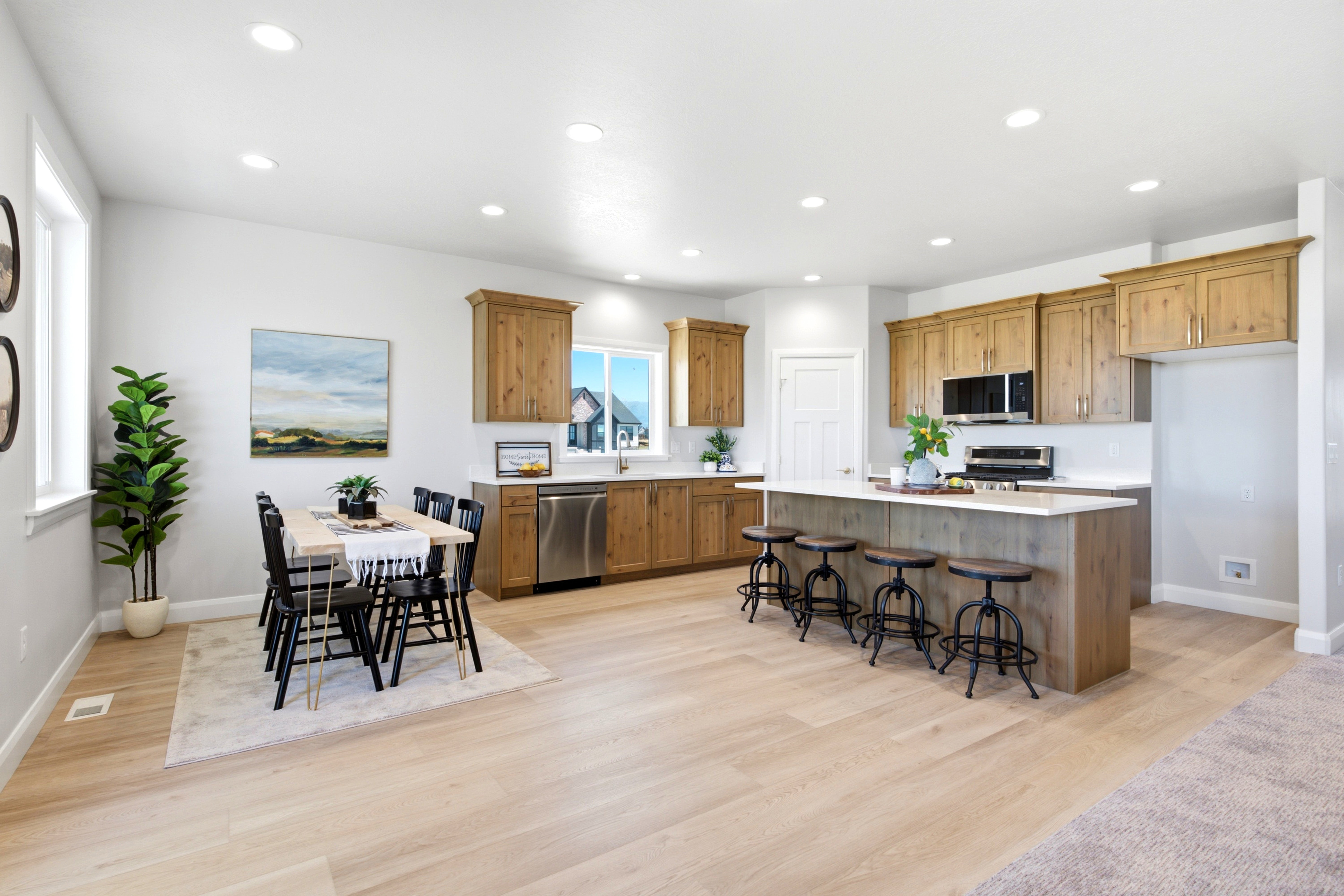 Open-concept kitchen featuring light wood-finish flooring, recessed lighting, and a white countertop island with seating