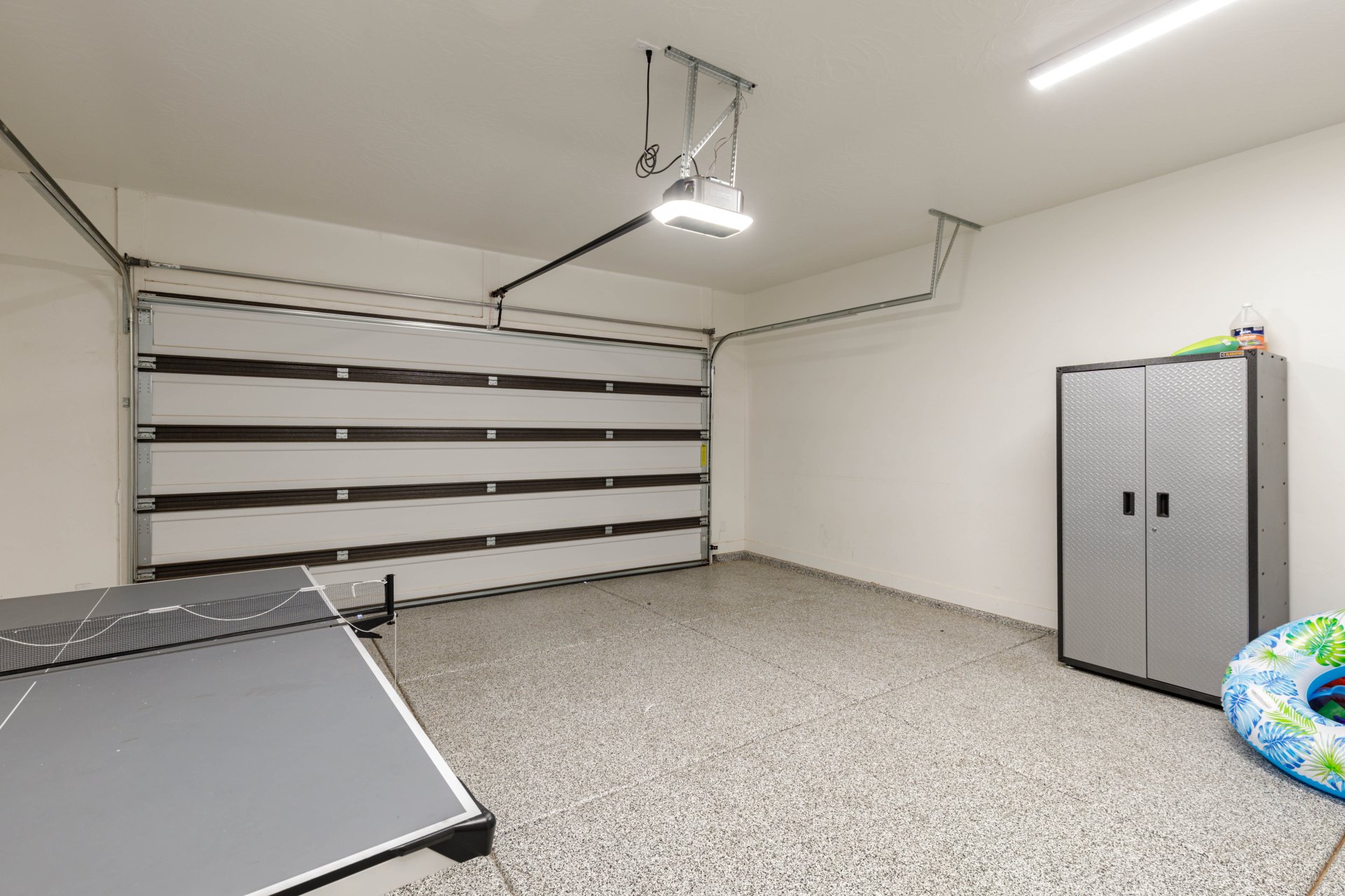 Attached garage featuring an automatic overhead door and a speckled epoxy flooring finish