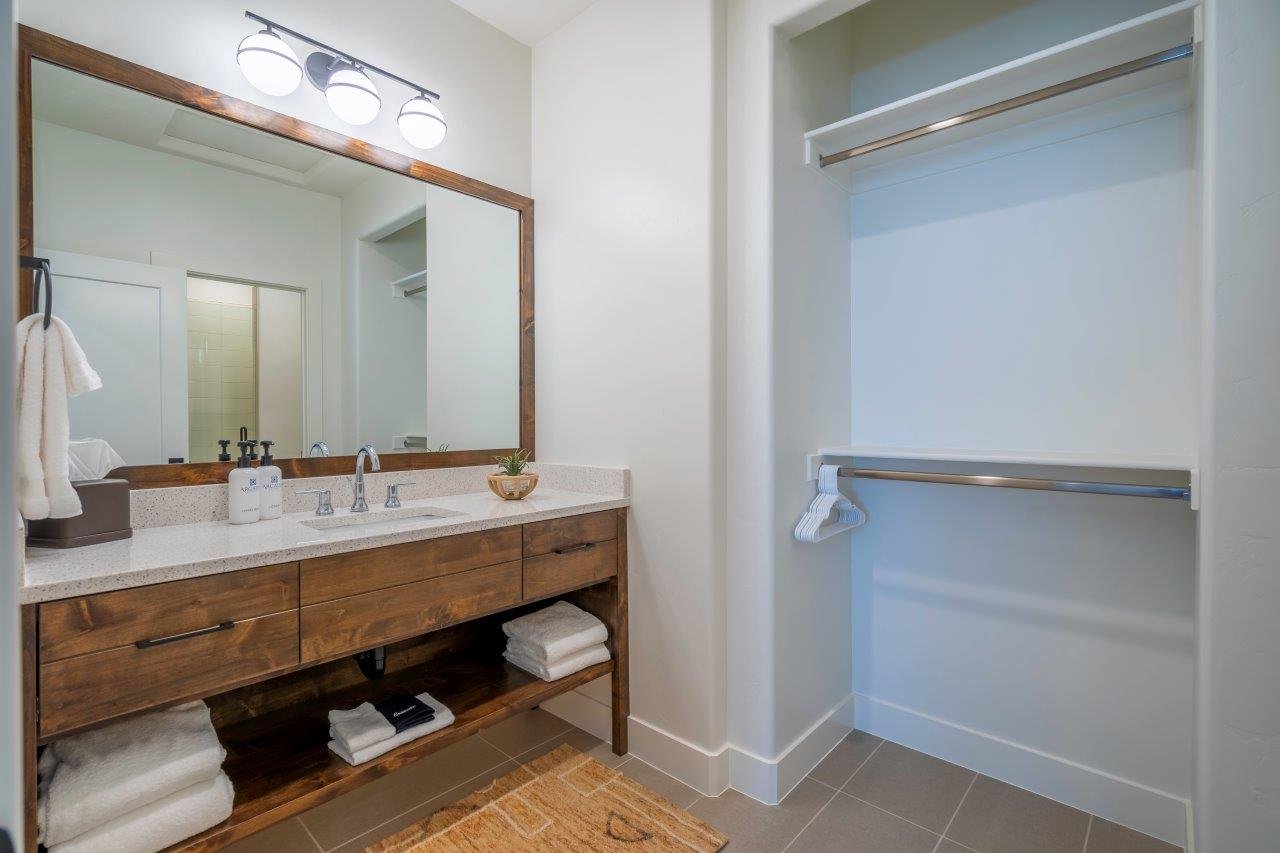 Bathroom vanity featuring a wood-finish cabinet with drawer storage, an open lower shelf, and a light-colored speckled countertop