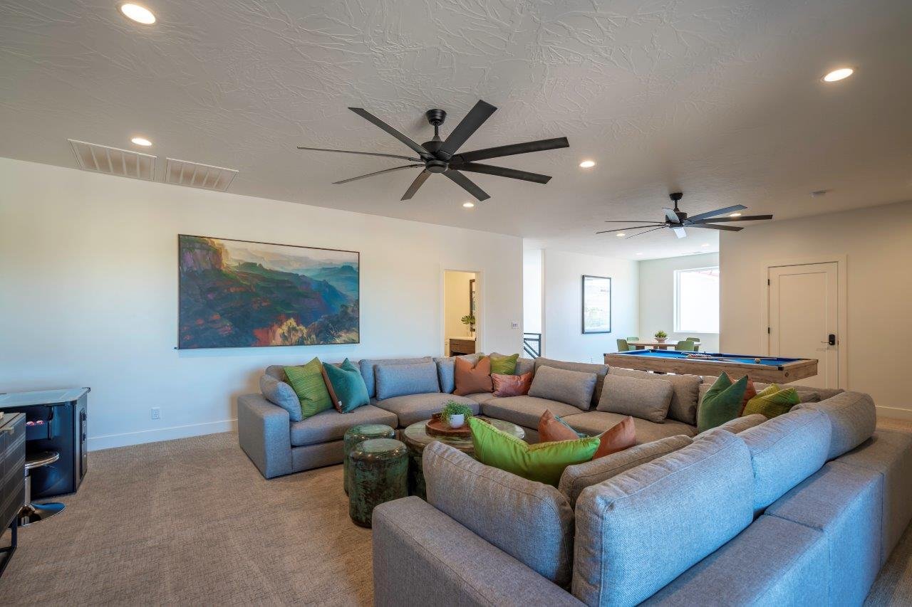 Spacious room featuring neutral carpet flooring, recessed lighting, and two multi-blade ceiling fans