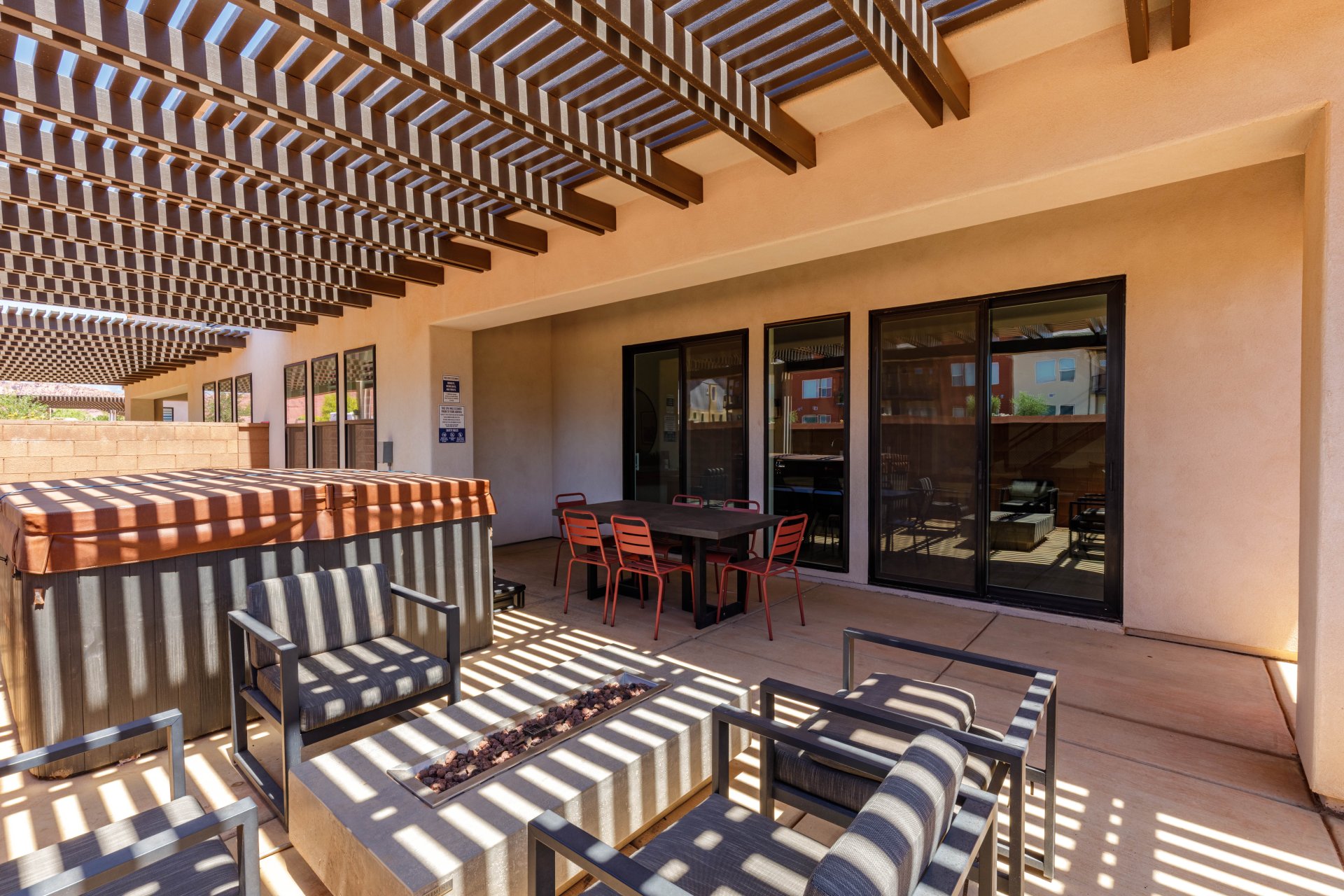 Expansive outdoor patio featuring a slatted pergola, built-in hot tub, and a modern fire pit
