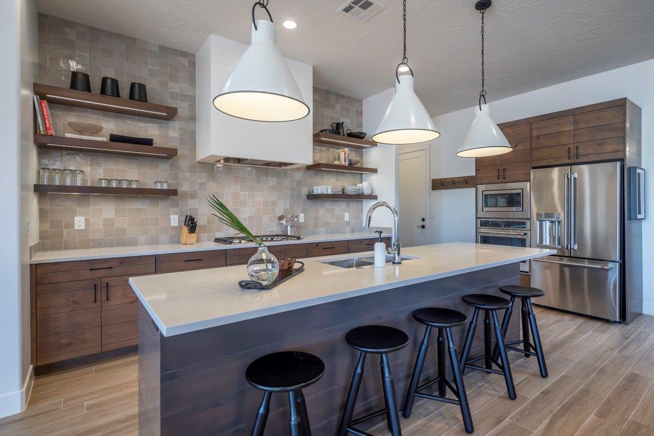 Contemporary kitchen featuring a large central island with a sink and seating, stainless steel appliances, open shelving, and rich wood-finish cabinetry