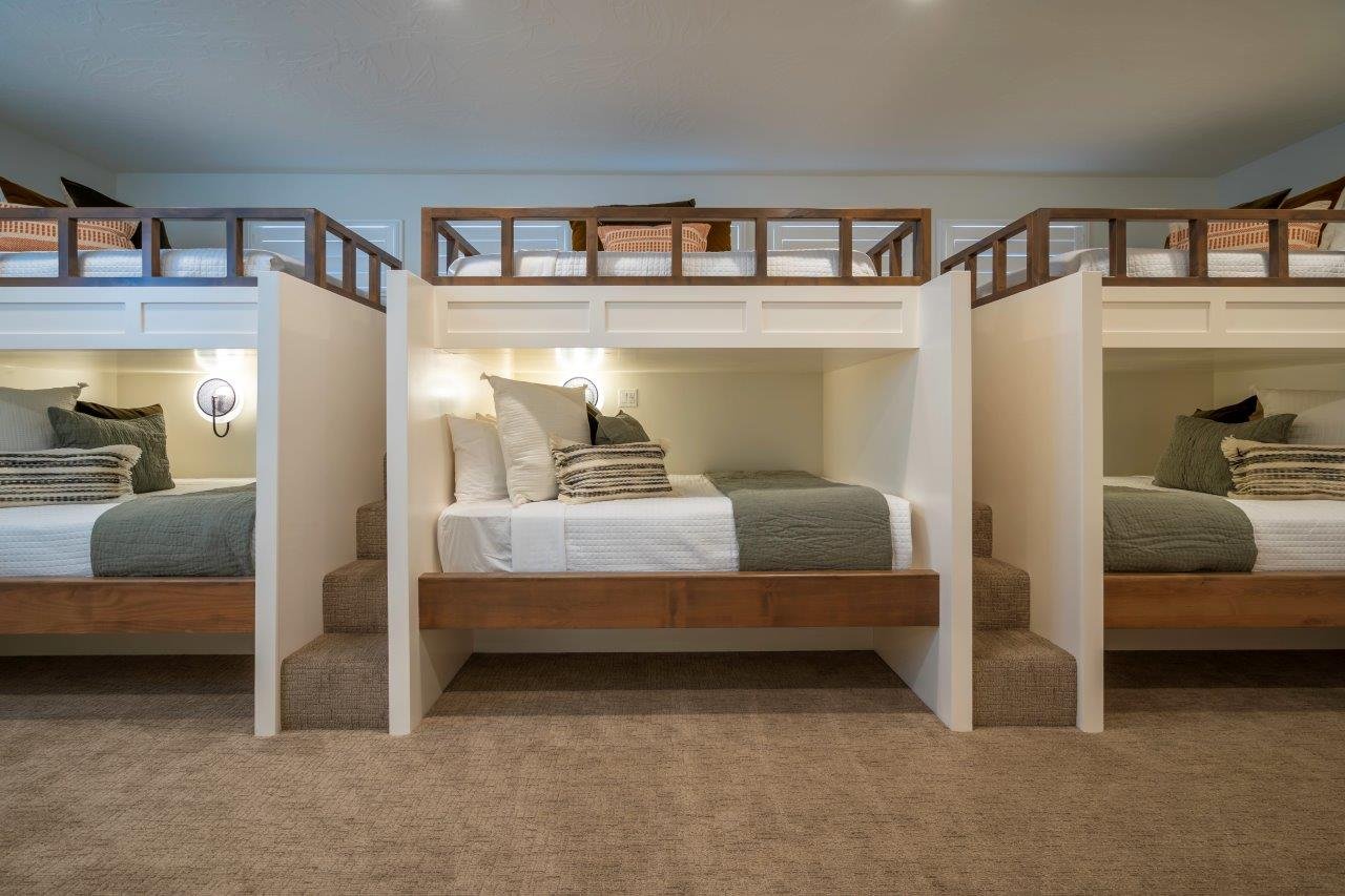 Built-in bunk beds featuring wood-finish frames, integrated wall sconces, carpeted stairs, and upper level railings