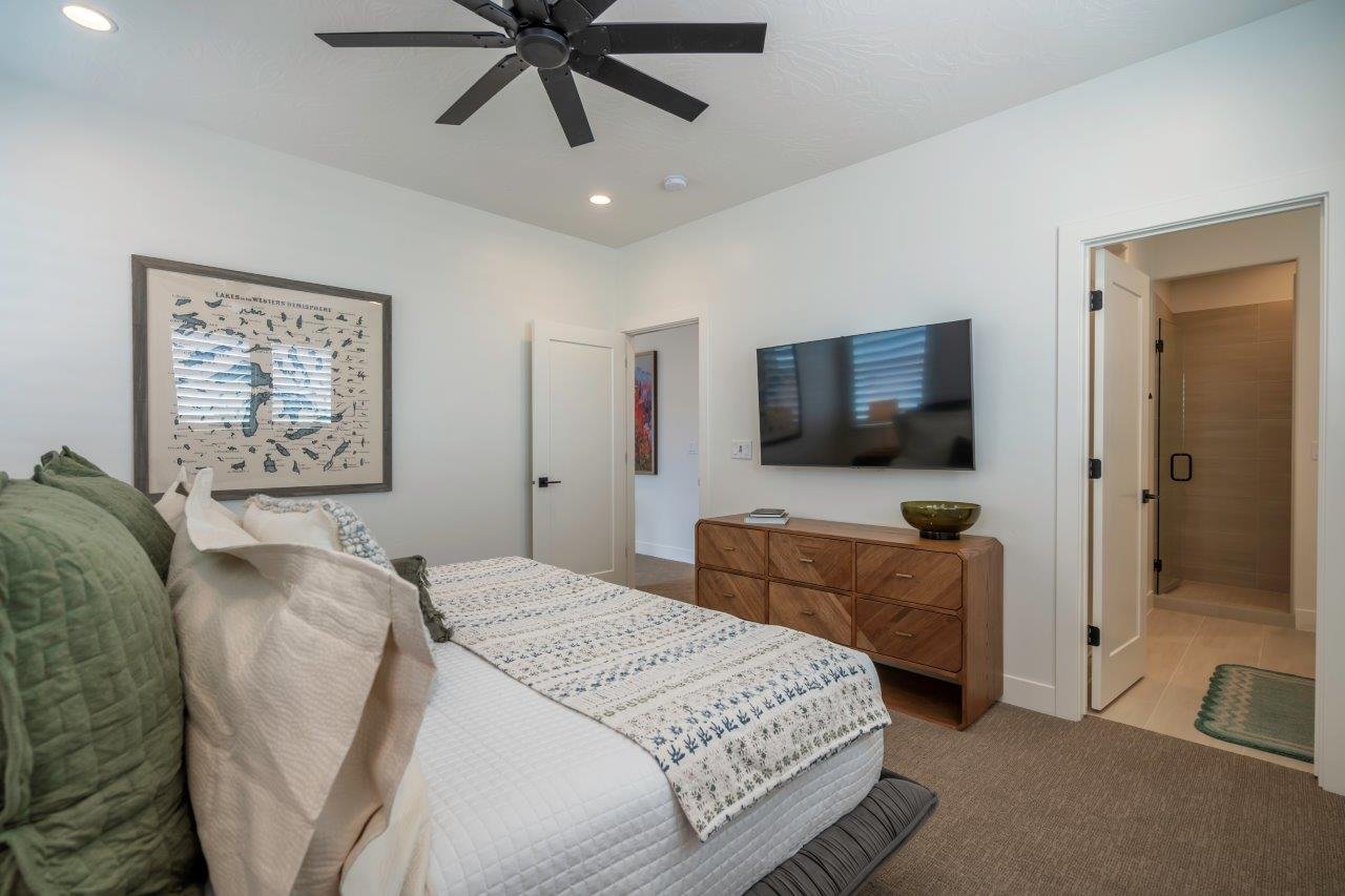 Recessed lighting and a black ceiling fan illuminate this room with textured carpeting