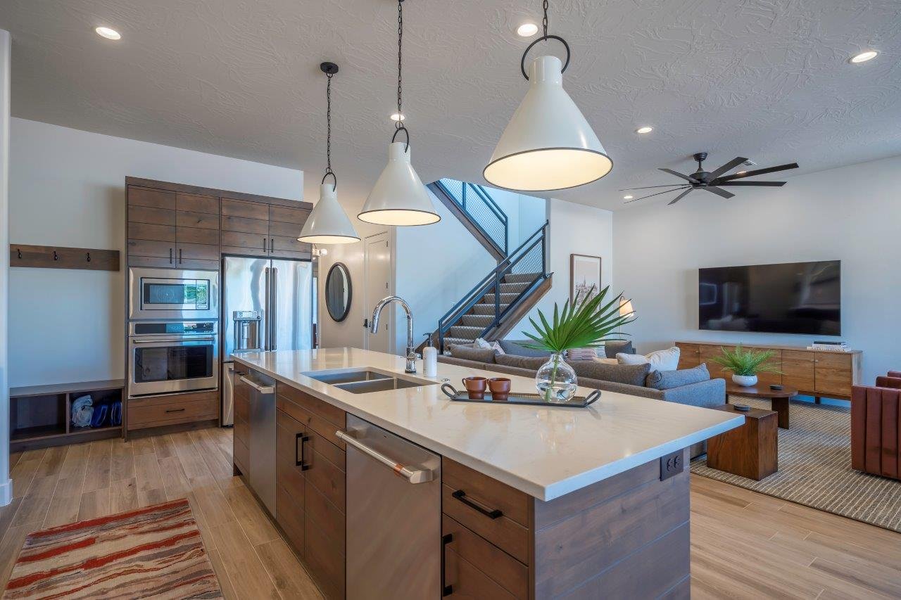 Gourmet kitchen featuring a large island with white stone countertops, stainless steel appliances, wood-finish cabinetry, and three pendant light fixtures