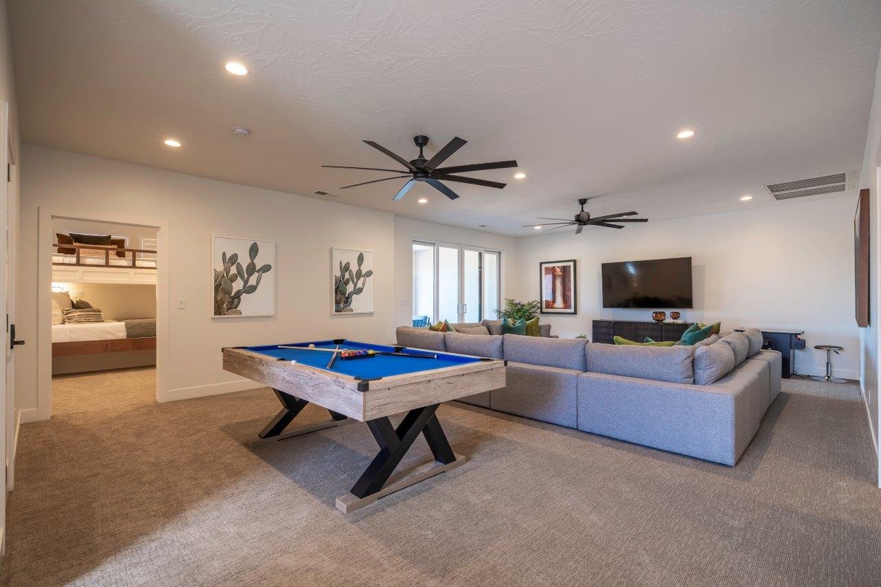 Spacious entertainment area featuring recessed lighting, two ceiling fans, and neutral carpeting