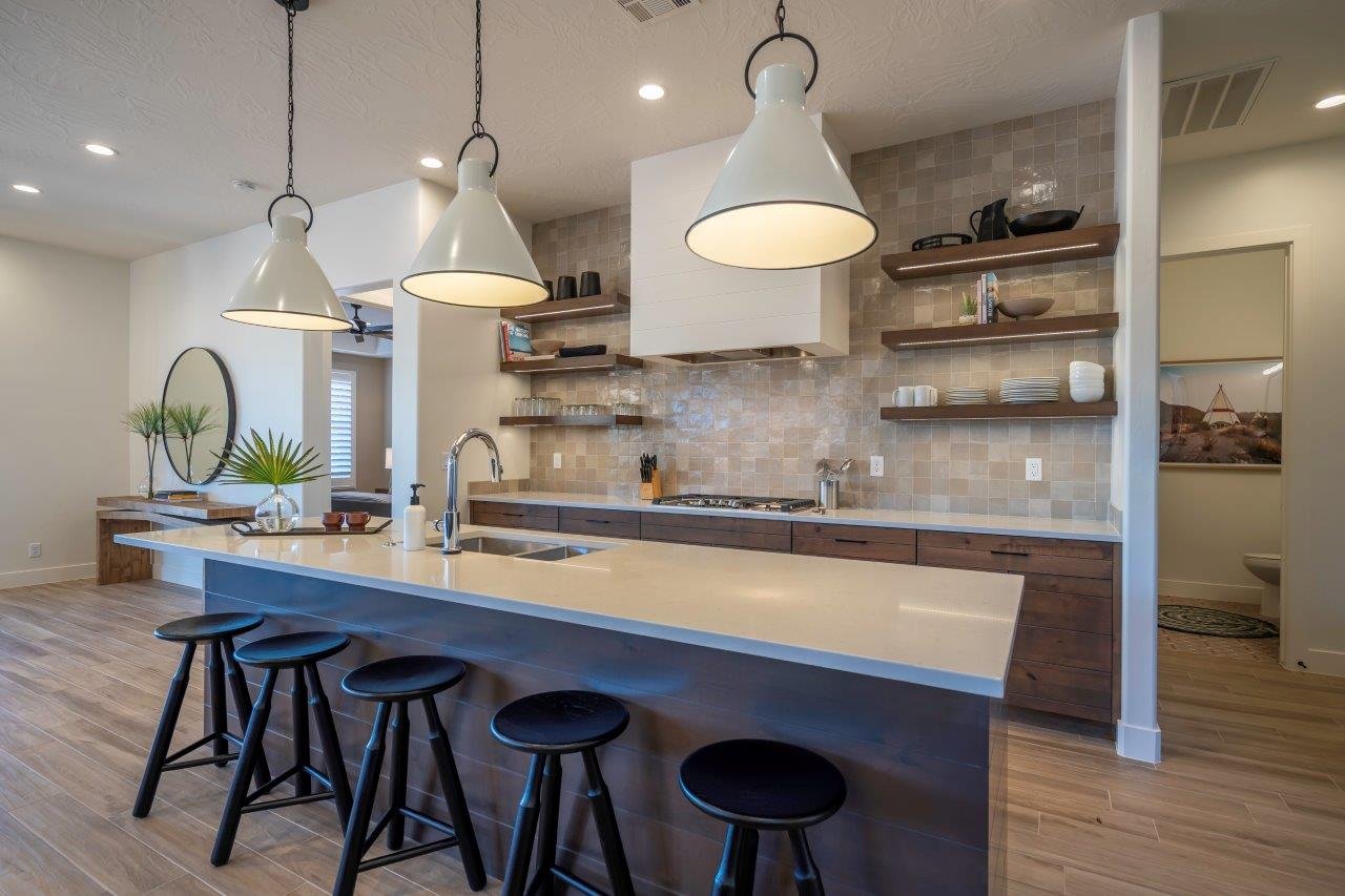 Contemporary kitchen featuring a large central island with seating, a stainless steel sink, and three pendant lights