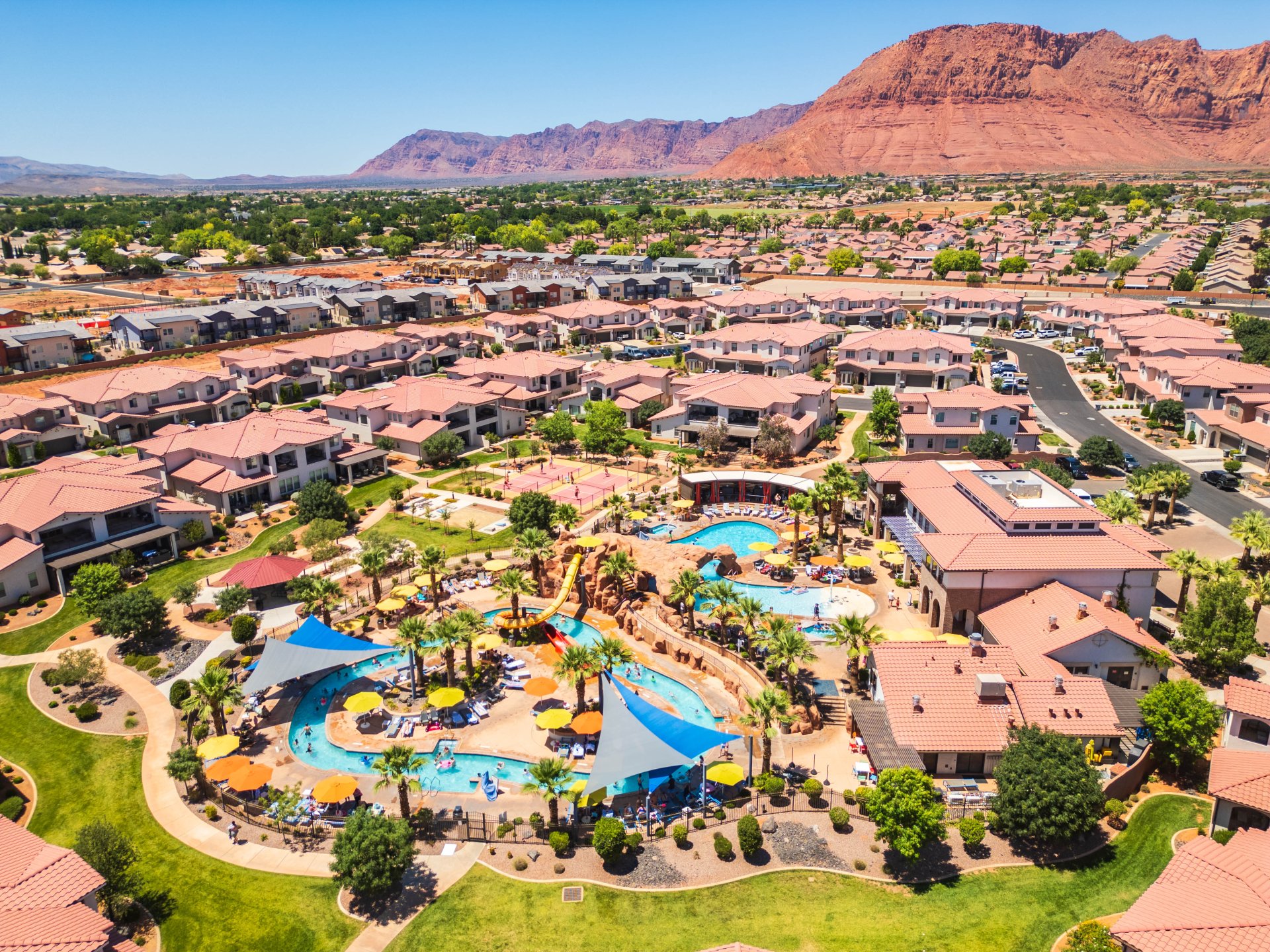 Expansive resort-style pool area with a lazy river, water slide, and shaded lounge spaces
