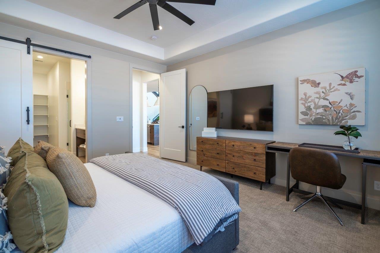 Carpeted bedroom with a tray ceiling and a ceiling fan