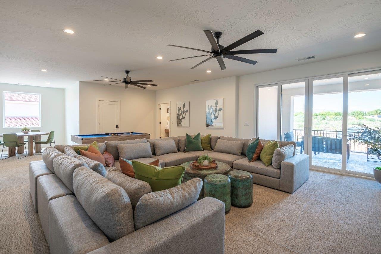 Spacious recreational room featuring light-colored carpet flooring, recessed lighting, and two ceiling fans
