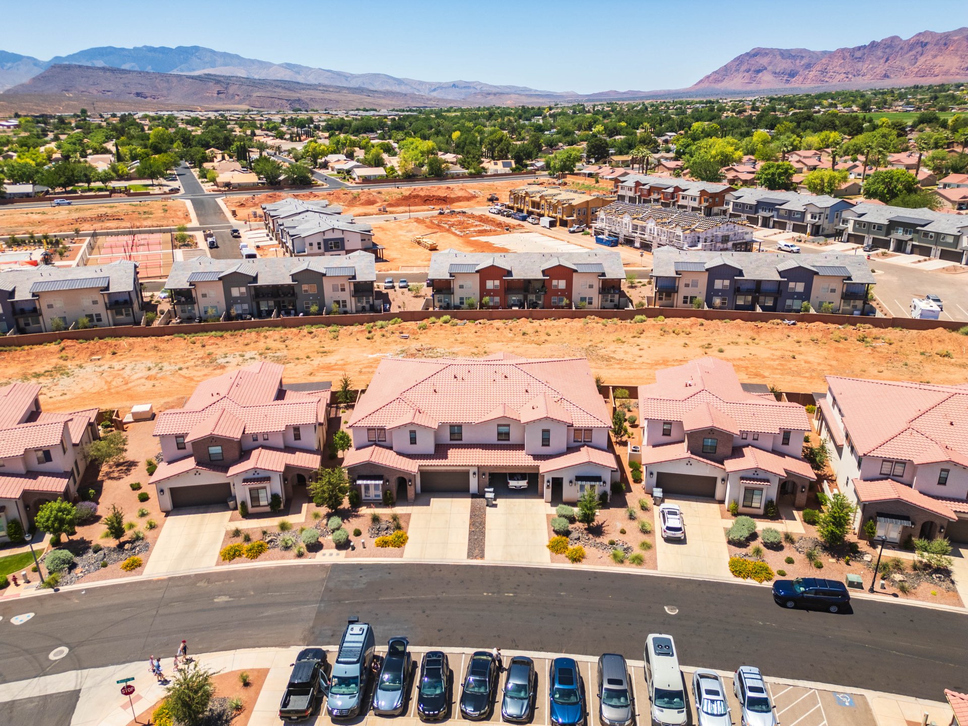 Residential development featuring a mix of multi-story townhomes and single-family residences with terracotta-style roof tiles and attached garages