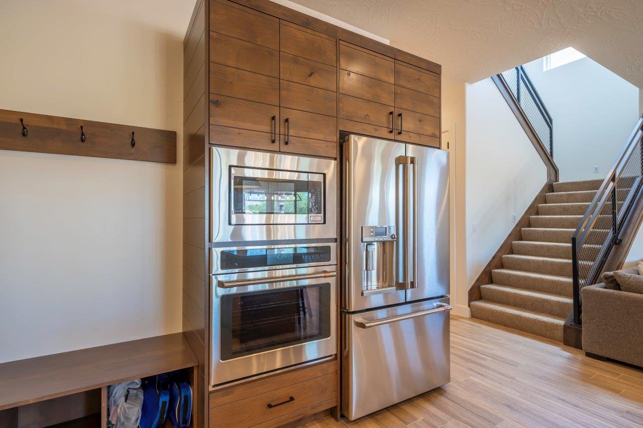 Built-in stainless steel appliances, including a microwave, oven, and refrigerator, integrated into custom wood-finish cabinetry