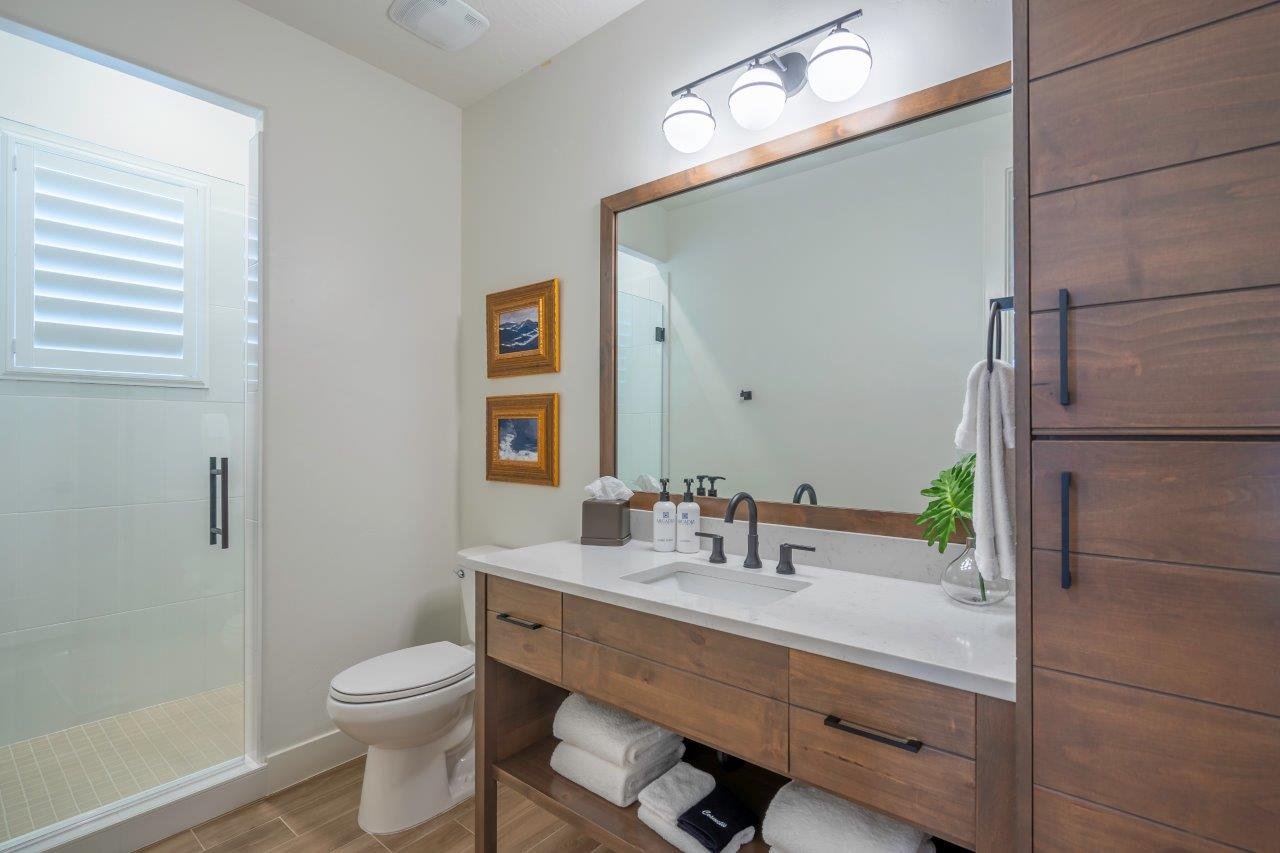Bathroom featuring a single vanity with stone countertop, undermount sink, and matte black faucet