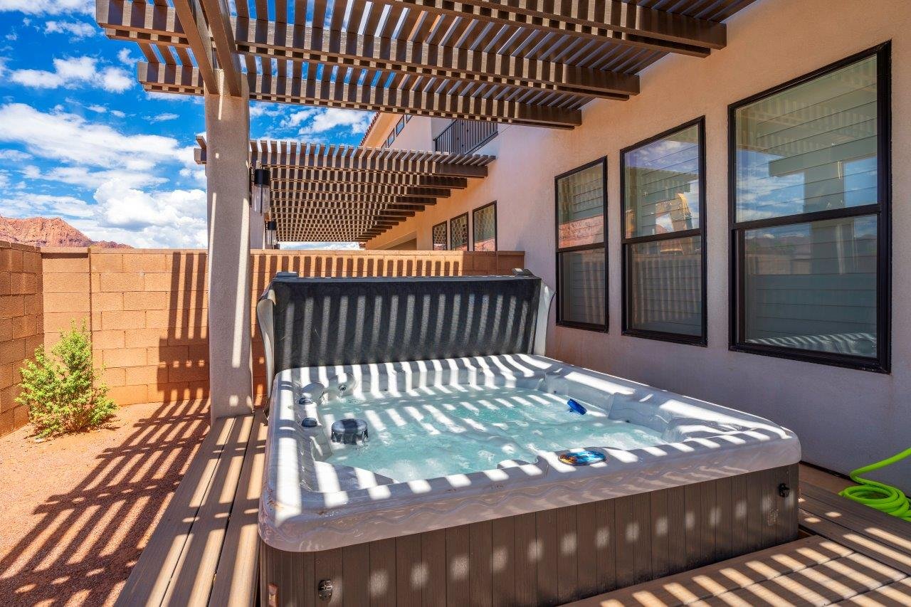 Outdoor spa set on wood-finish decking with a slatted pergola overhead