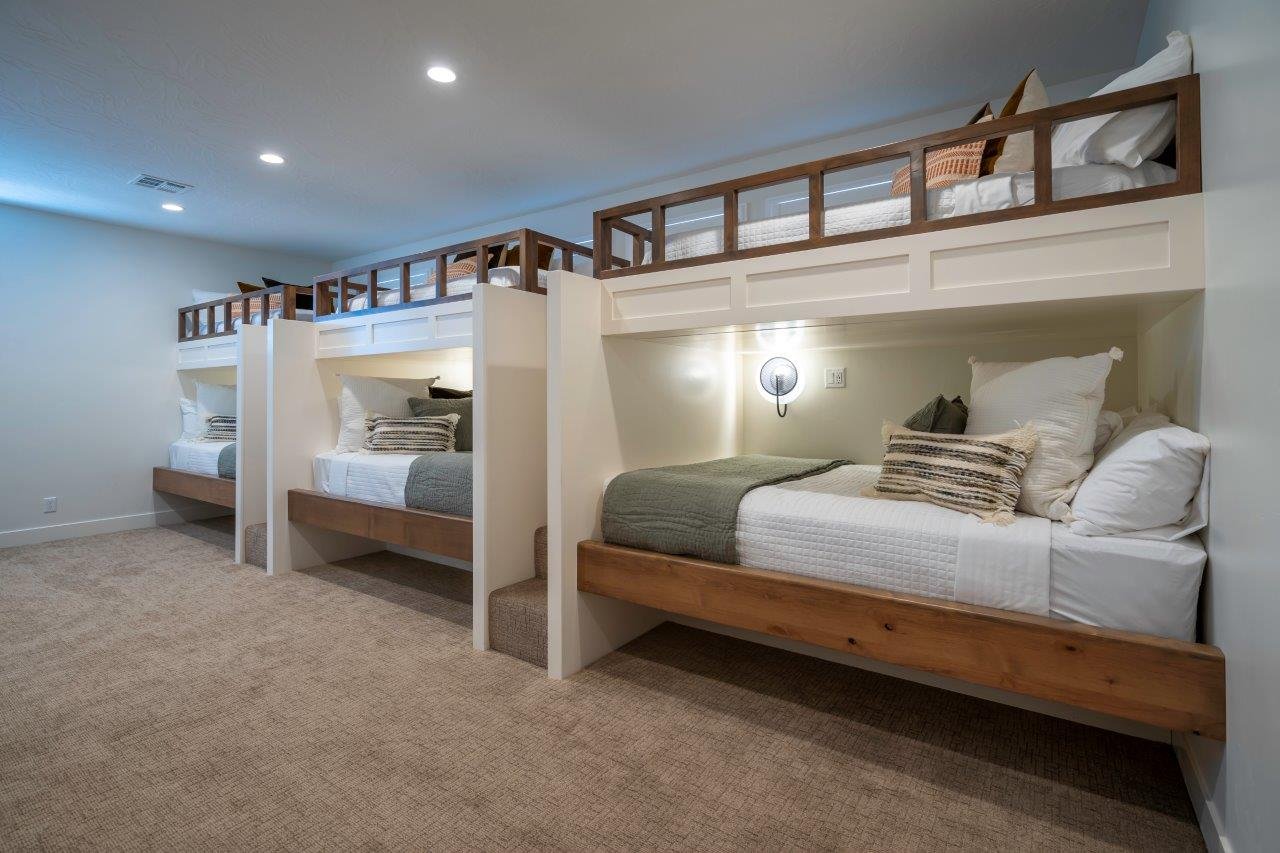 Built-in bunk beds with natural wood bases, white paneled surrounds, and integrated steps