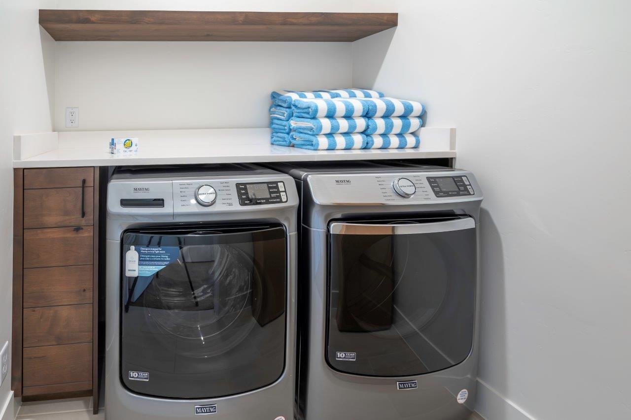 Laundry area featuring a floating wood shelf, white countertop, and built-in wood-finish cabinetry