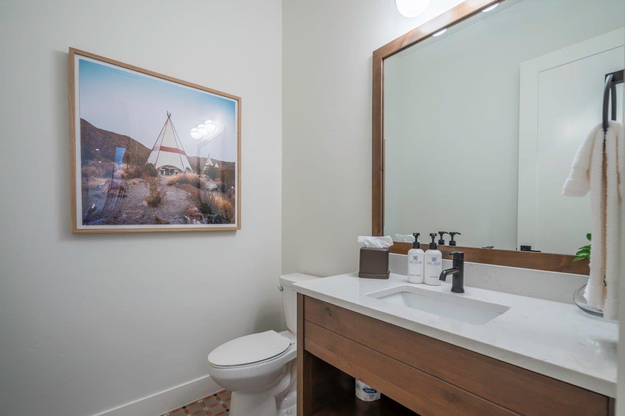Powder room featuring a wood-finish vanity with an integrated rectangular sink and a single-handle matte black faucet