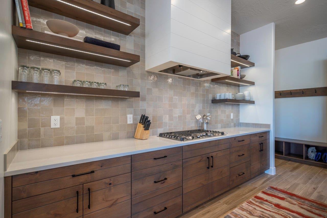 Modern kitchen featuring wood-finish cabinetry, light-toned countertops, and a tile backsplash