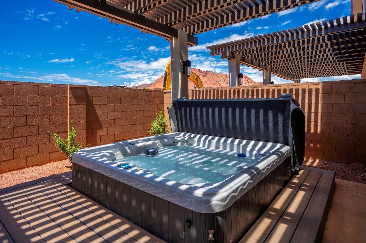 Outdoor spa with a slatted pergola, composite decking, and block wall surround