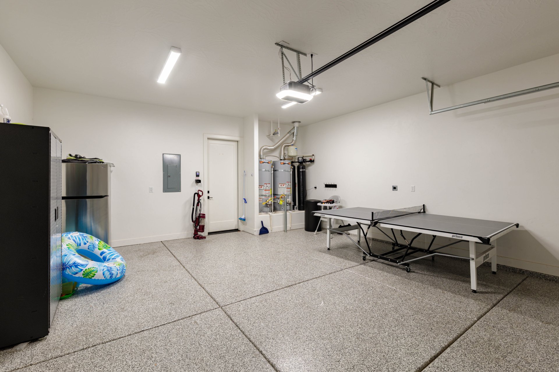 Spacious garage featuring a durable epoxy-coated floor, bright overhead lighting, and white painted walls