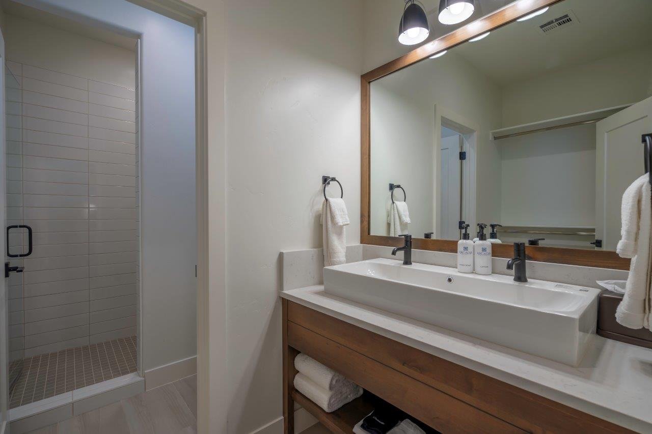 Modern bathroom featuring a double vanity with an integrated rectangular sink, light-toned countertop, and wood-finish cabinetry