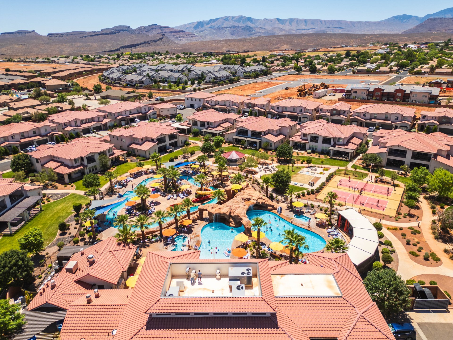 Expansive resort-style swimming pool complex featuring multiple pools, water slides, and rock formations