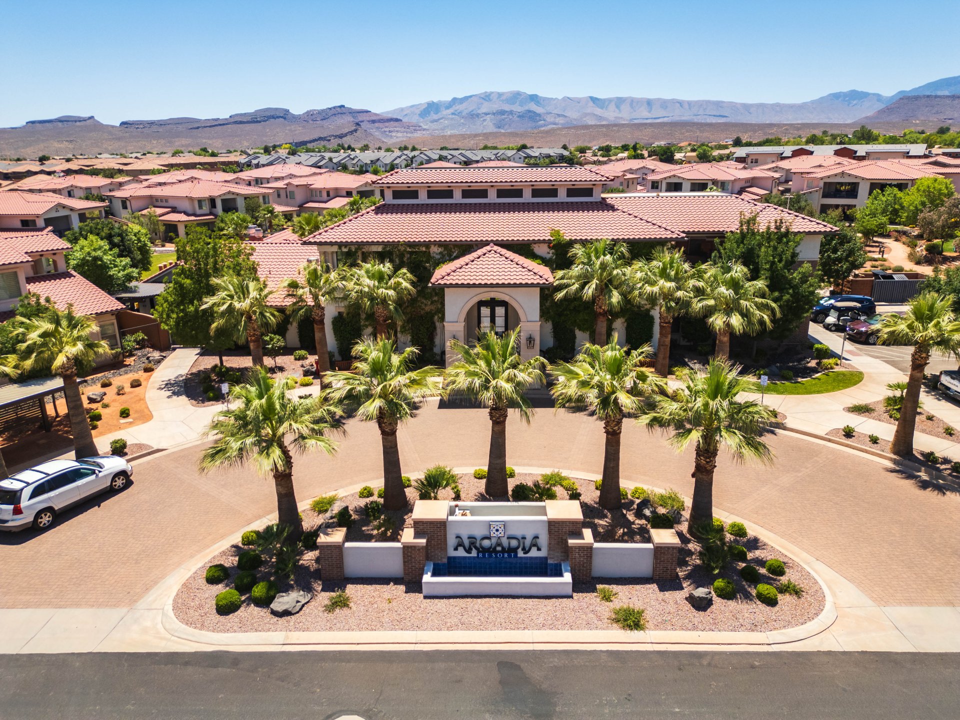 Entryway with a prominent welcome sign, surrounded by mature palm trees and desert landscaping